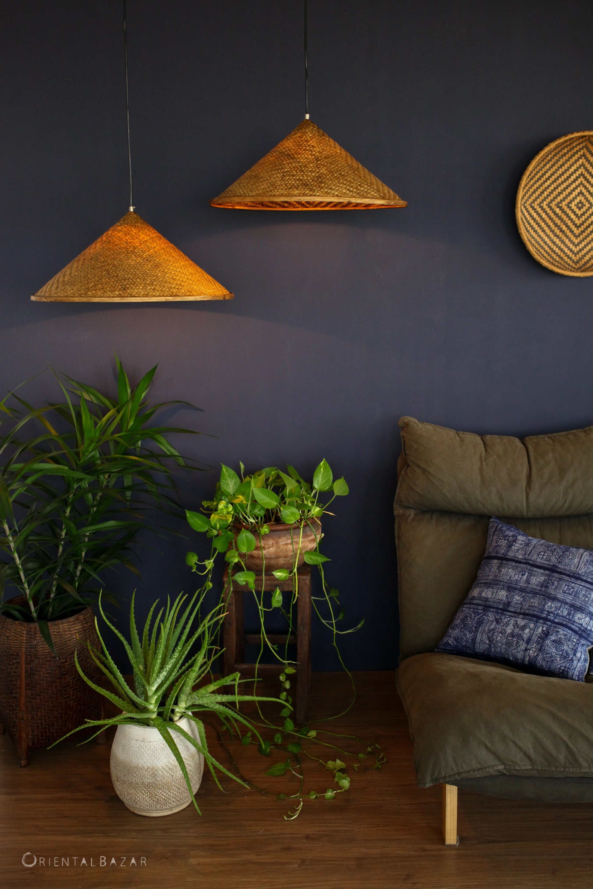 Living room with bamboo pendant lamps, plants, and a green-brown sofa.