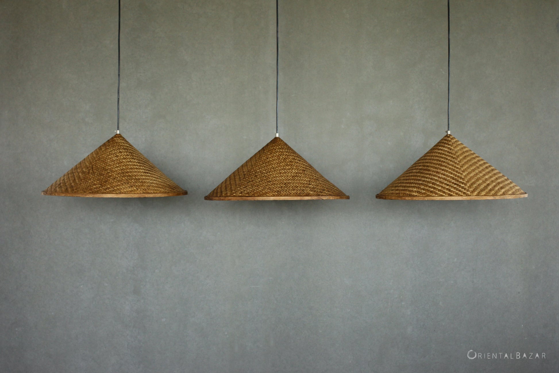 Three woven bamboo pendant lights hanging against a plain wall.