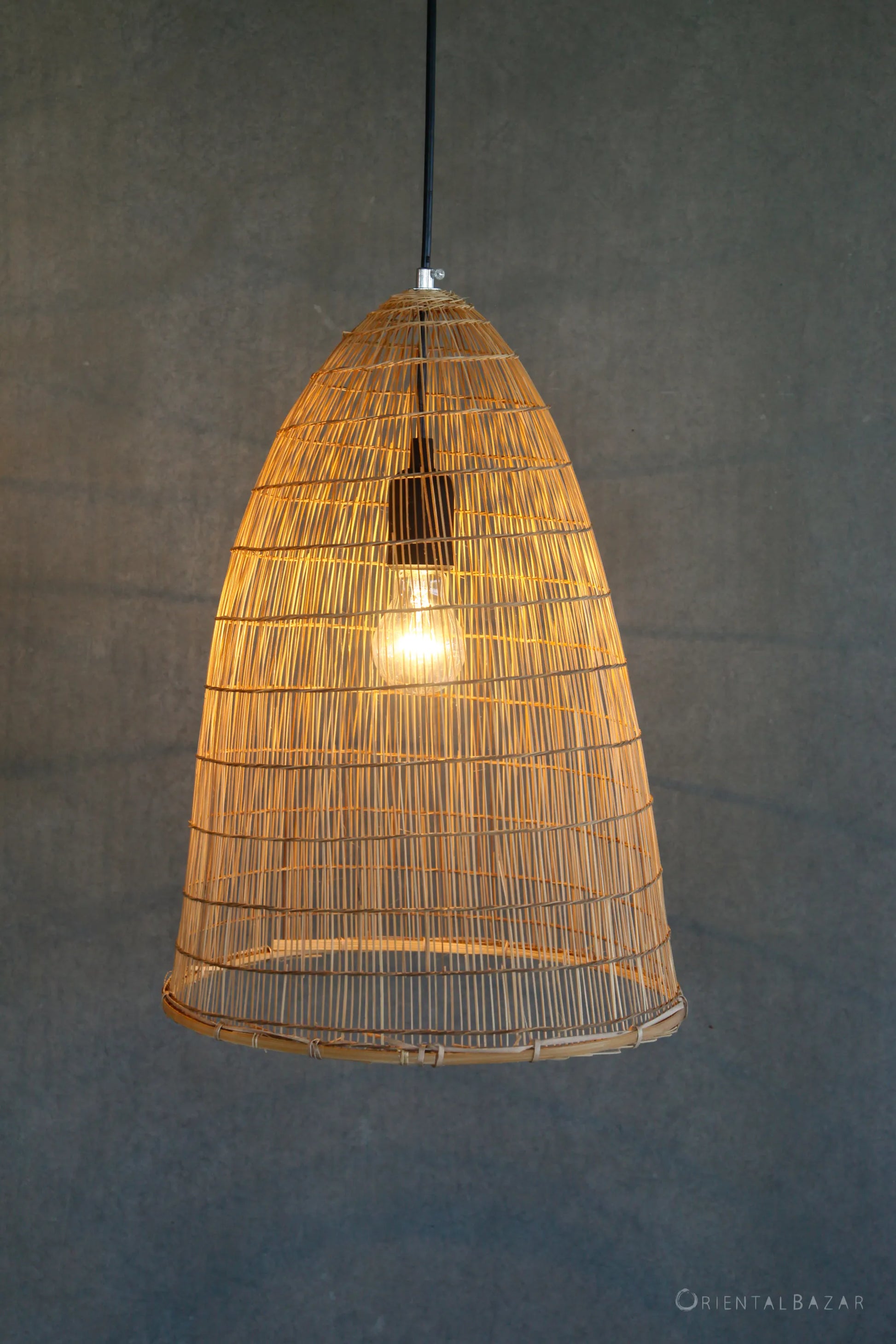 Woven bamboo pendant light against a gray background
