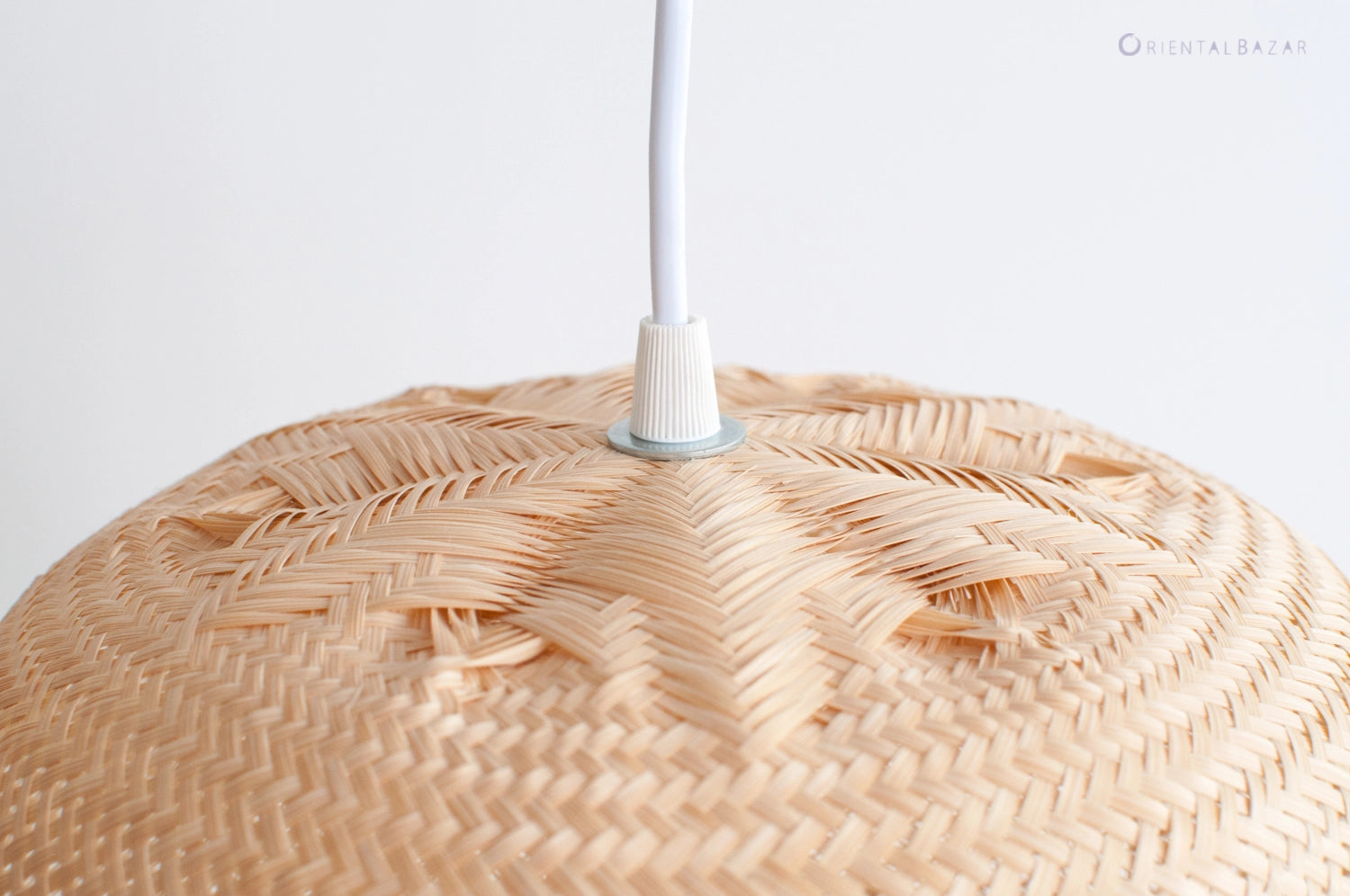 Close-up of a woven bamboo pendant light with white cord against a white background