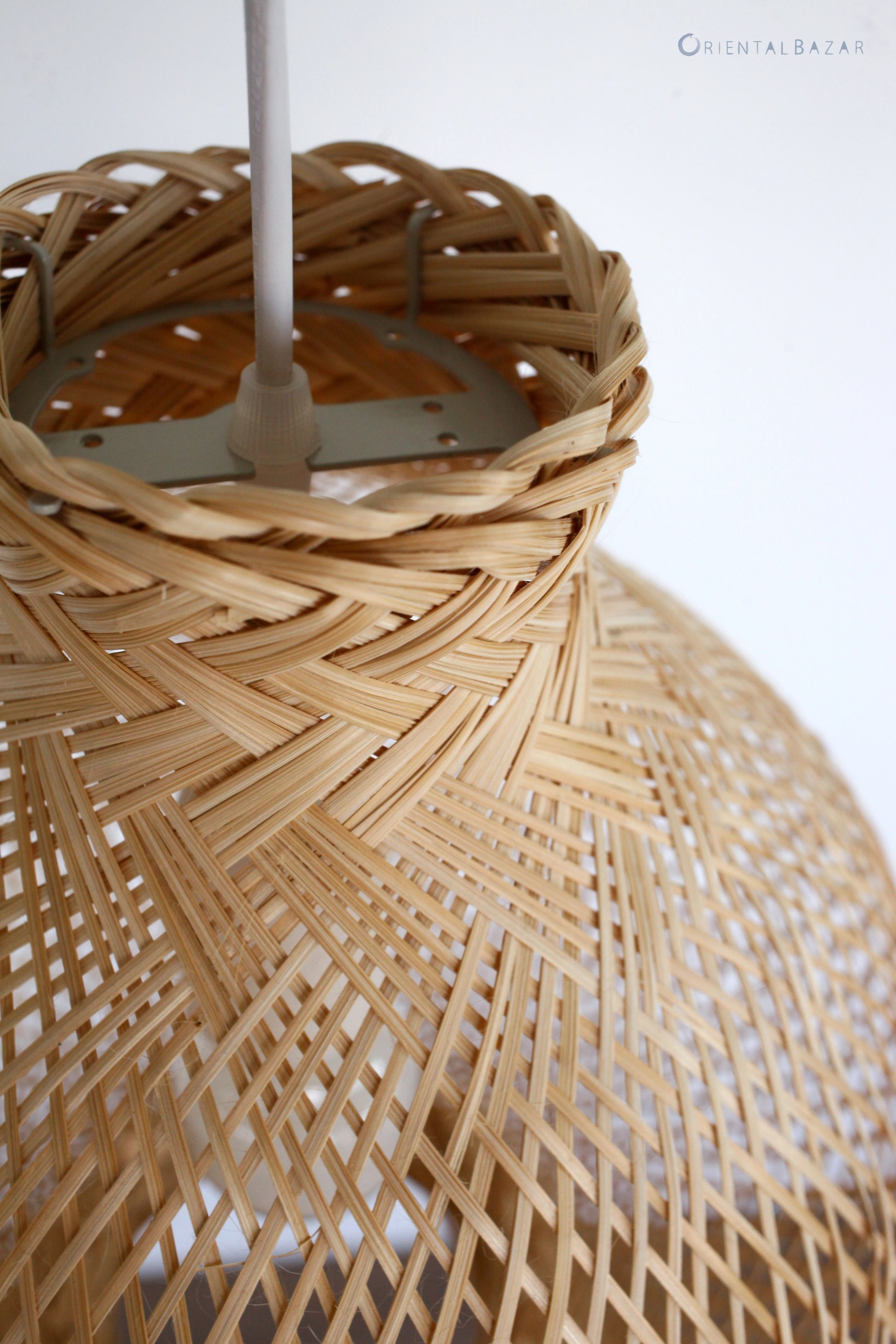 Close-up of a woven bamboo lampshade with a white ceiling cord fixture.