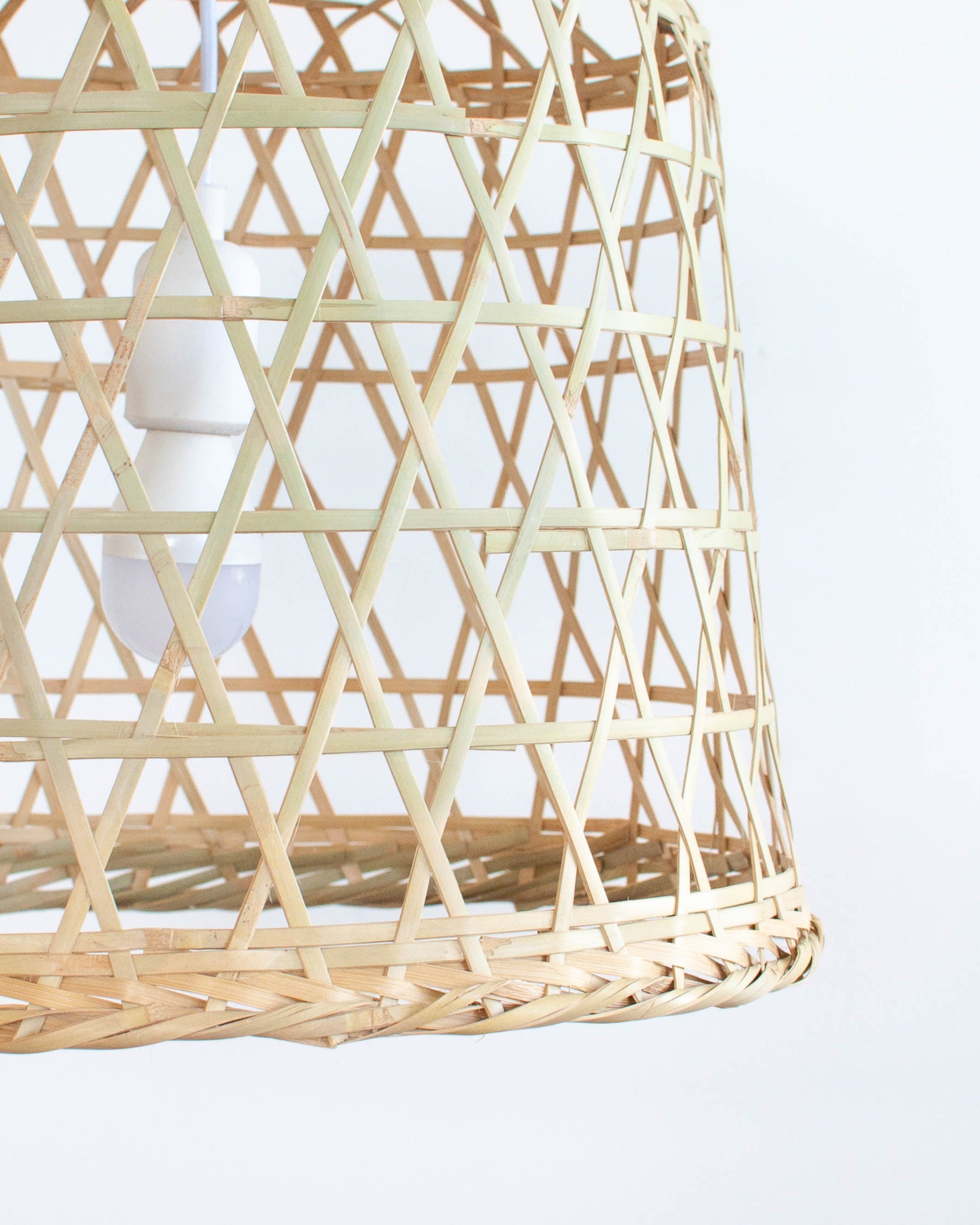 Woven bamboo pendant light against a white background