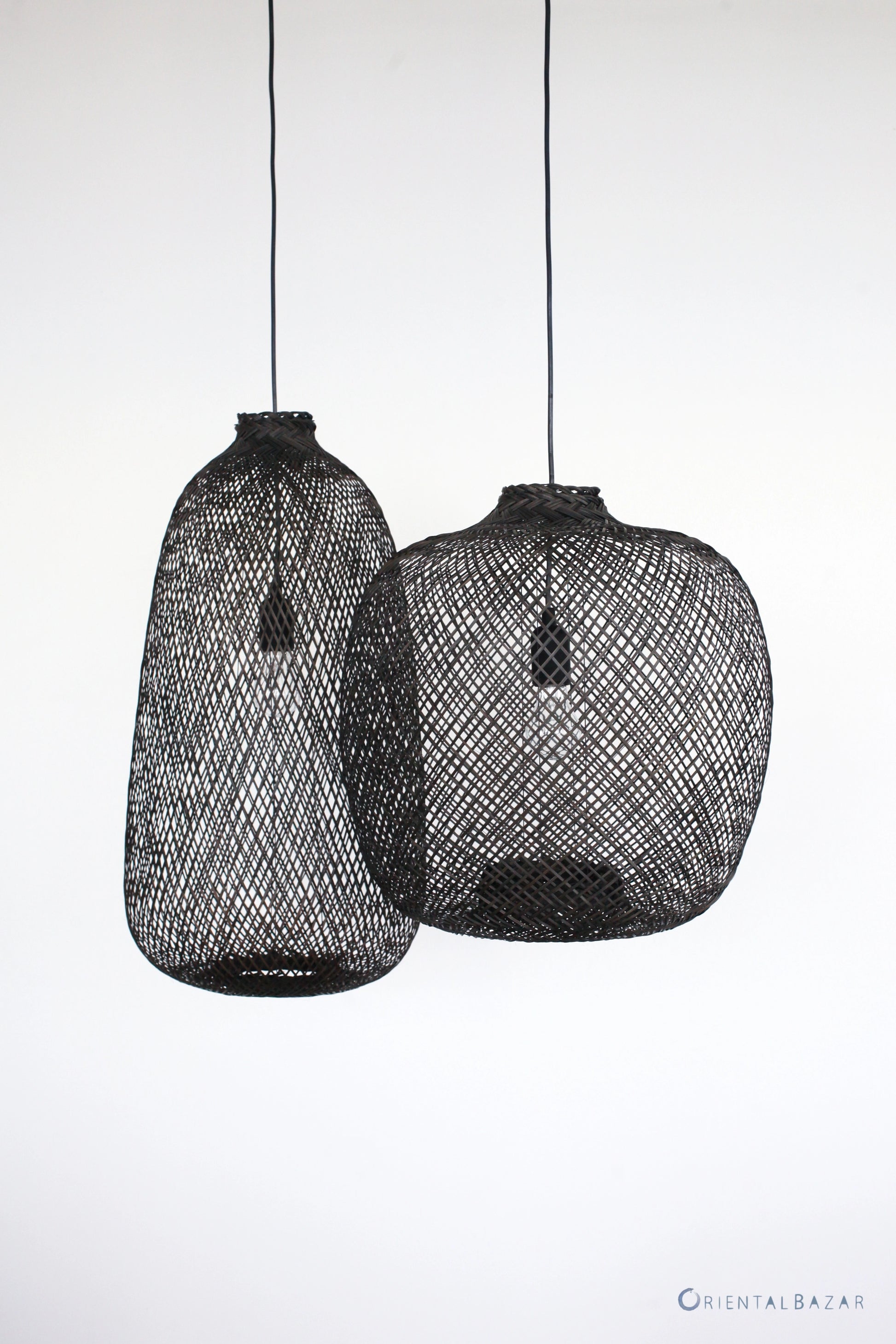 Two black woven bamboo pendant lights on a white background