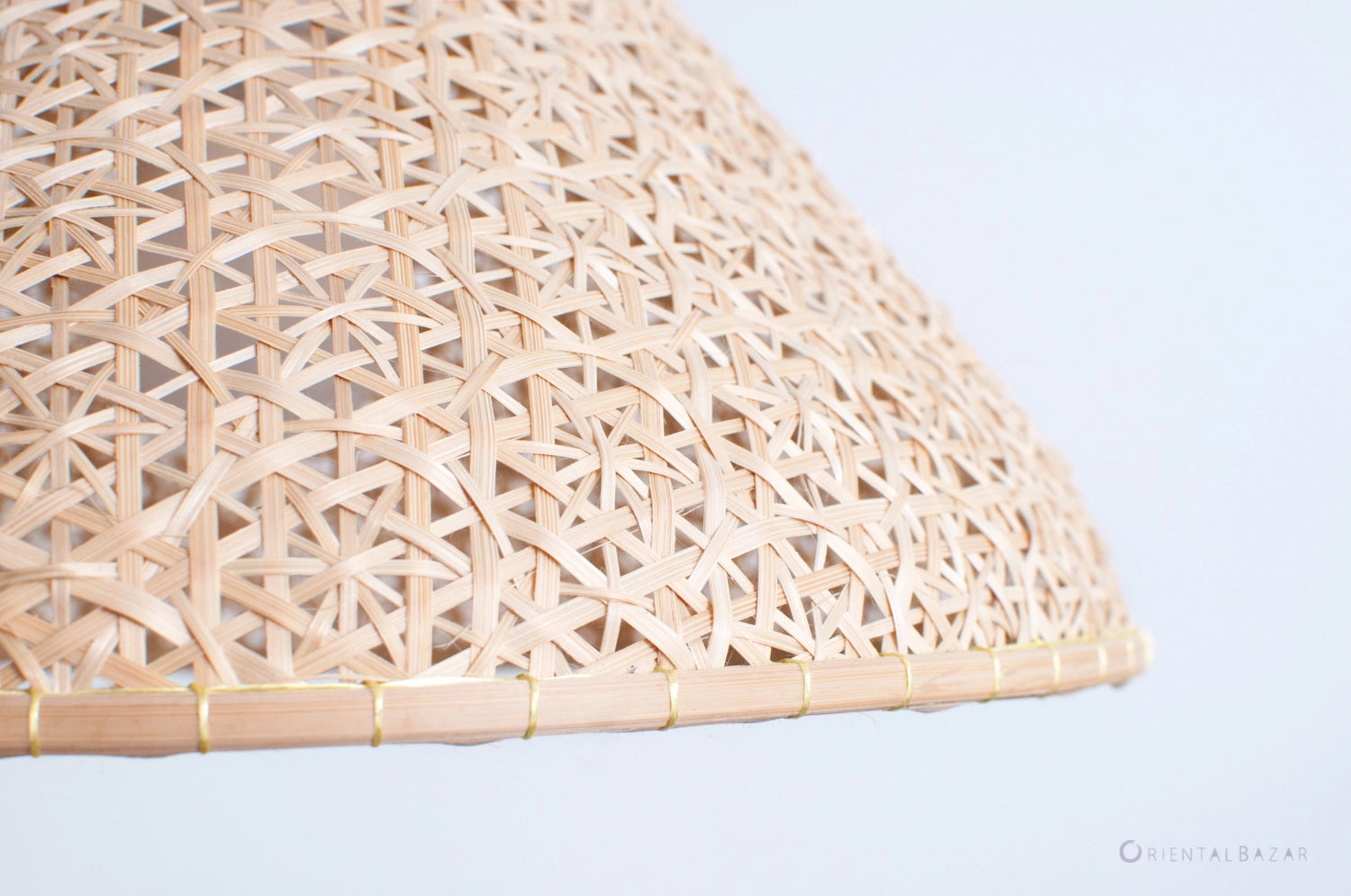 Close-up of a woven bamboo lampshade on a light gray background