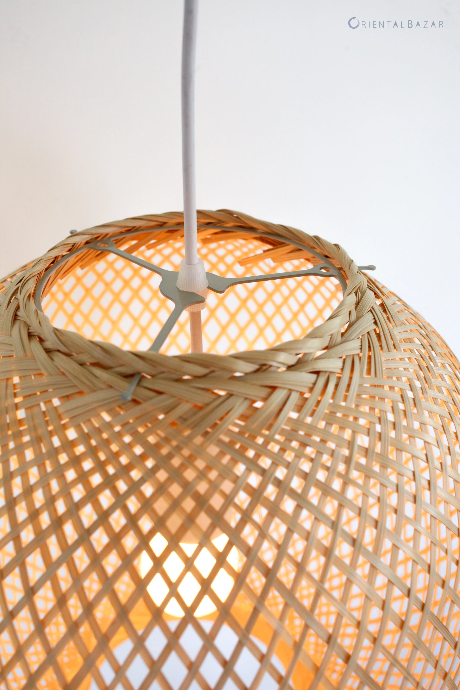 Closeup of a woven bamboo pendant light with a ceiling fixture on a white background