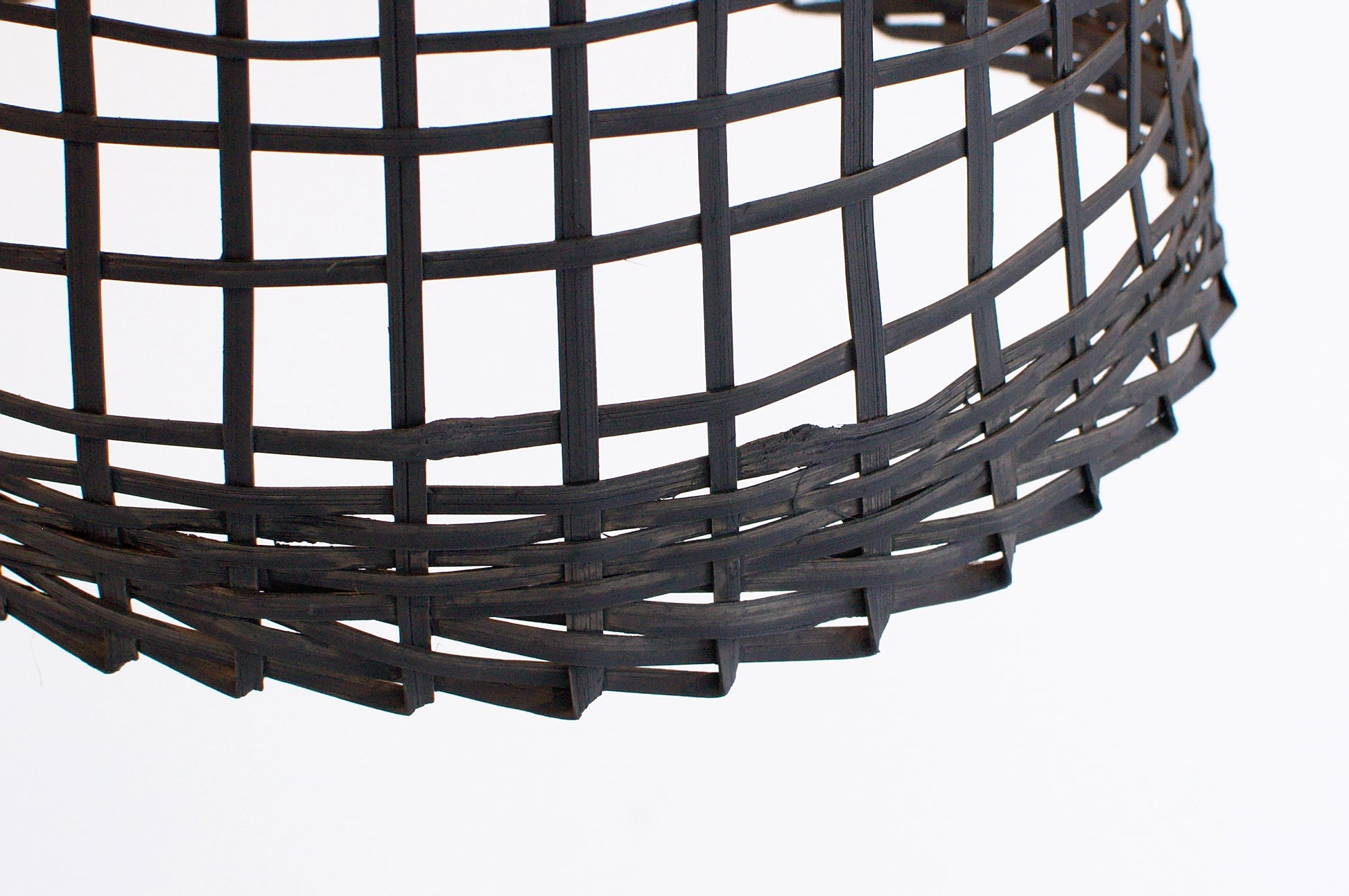 Close-up of a black bamboo basket lamp on a white background