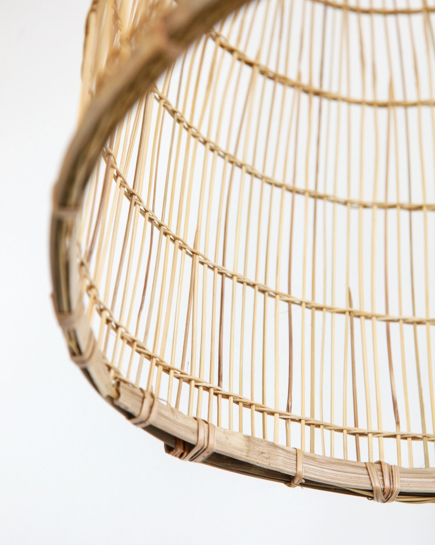 Close-up of the bottom of a woven bamboo lamp on a white background