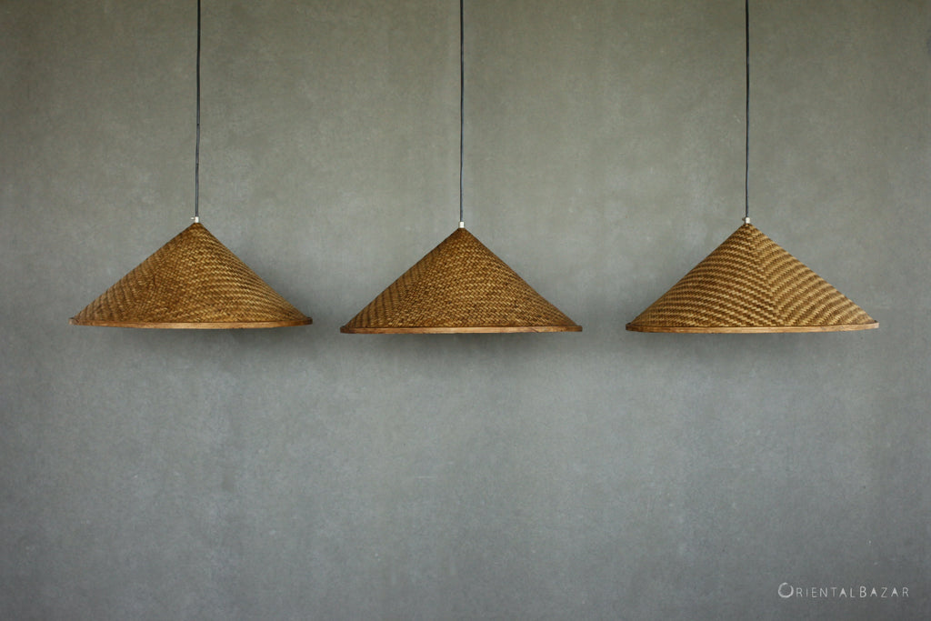 Three woven bamboo pendant lights hanging against a plain wall.