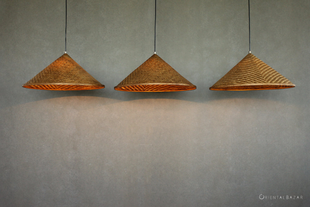 Three woven bamboo pendant lights hanging against a plain background