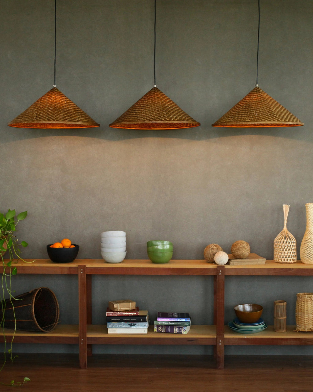 Wooden shelf with decorative items against a gray wall with bamboo pendant lights