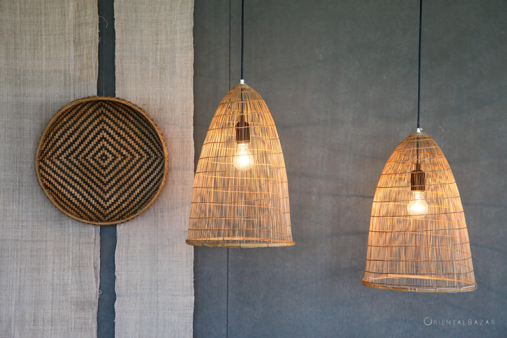 Woven bamboo pendant lights hanging against a textured gray wall next to hanging decorative bamboo basketry and hemp textiles 