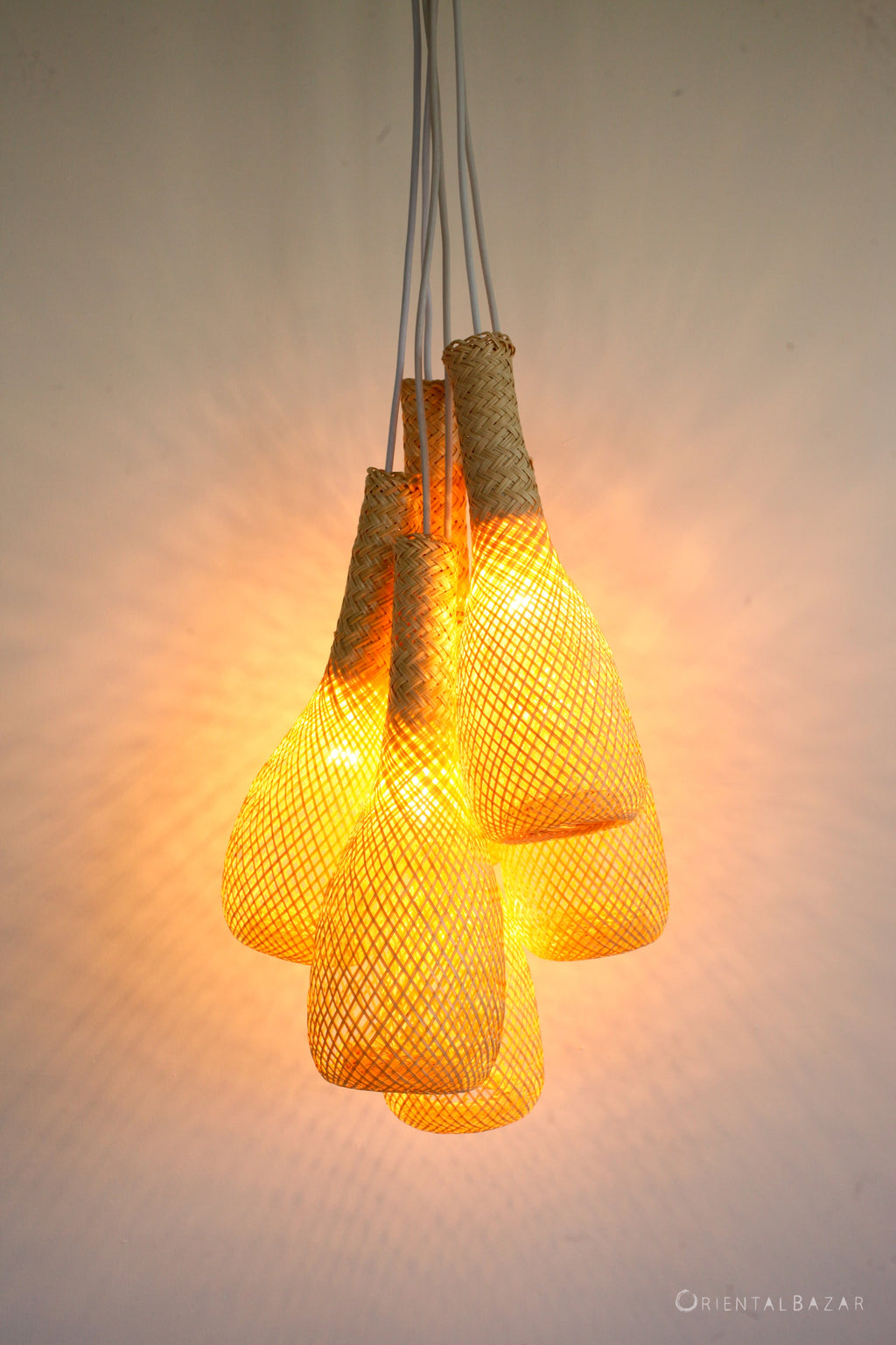 Bunch of woven bamboo pendant lights casting a warm glow on a neutral background