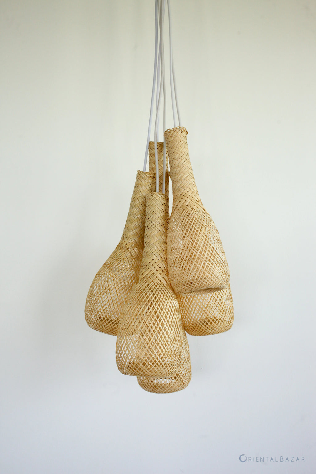Set of woven bamboo basket lamps hanging against a plain background