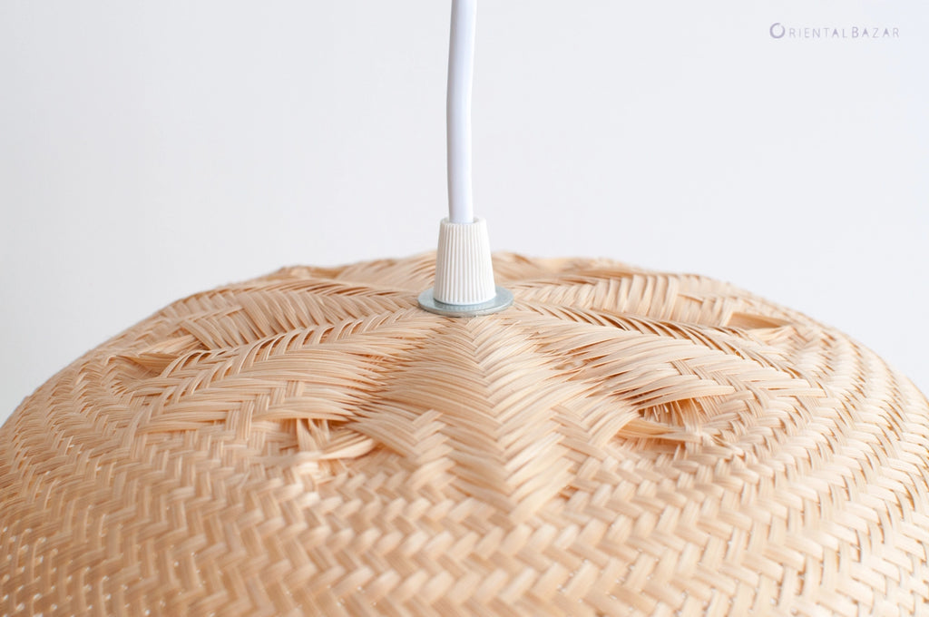 Close-up of a woven bamboo pendant light with white cord against a white background