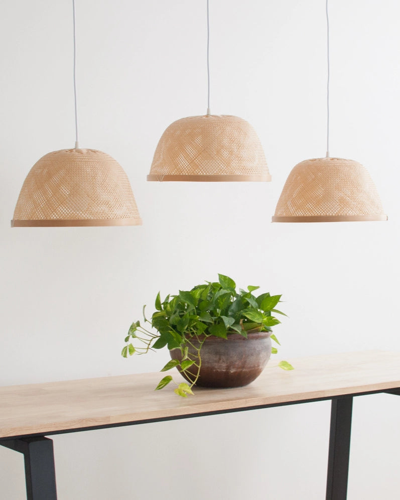Wooden table with a plant and three bamboo bowl lamps on a white background
