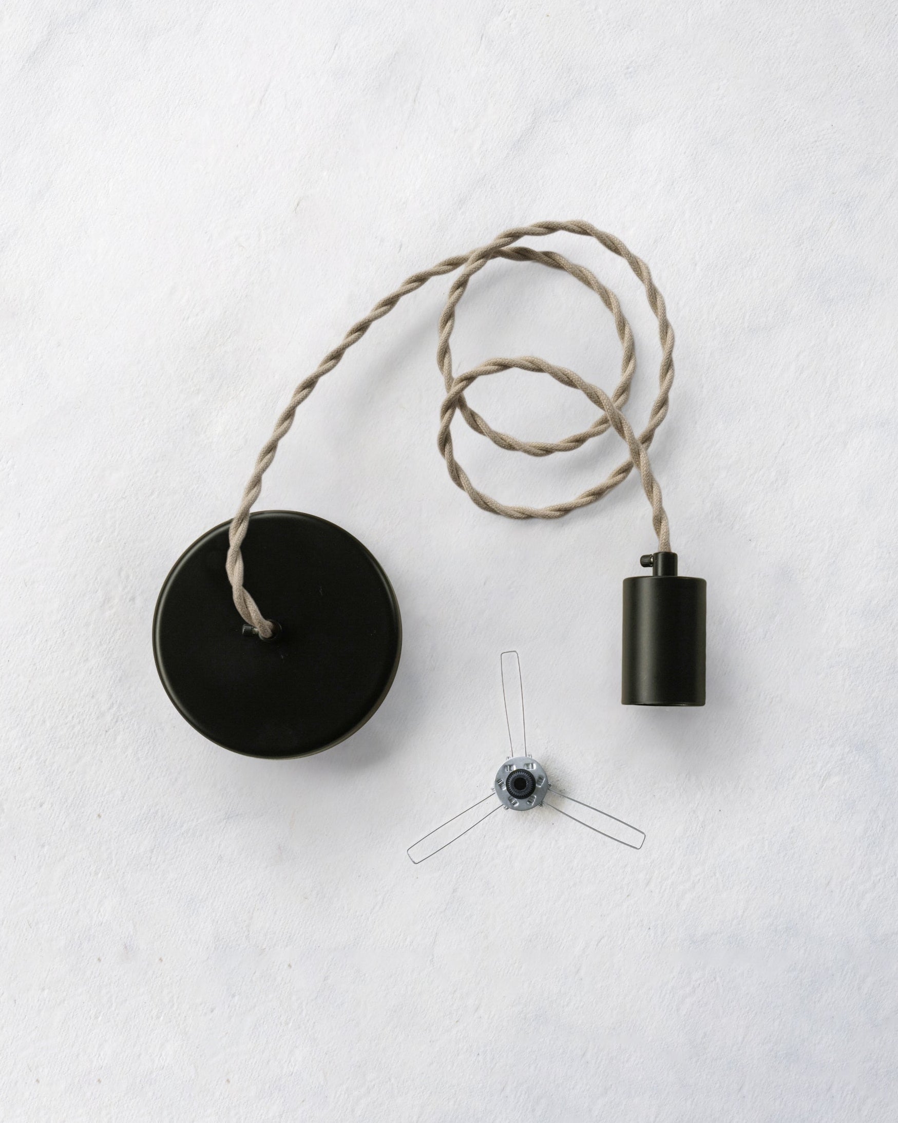 Pendant lamp with beige linen cord, black canopy and socket and a lampshade holder on a white background