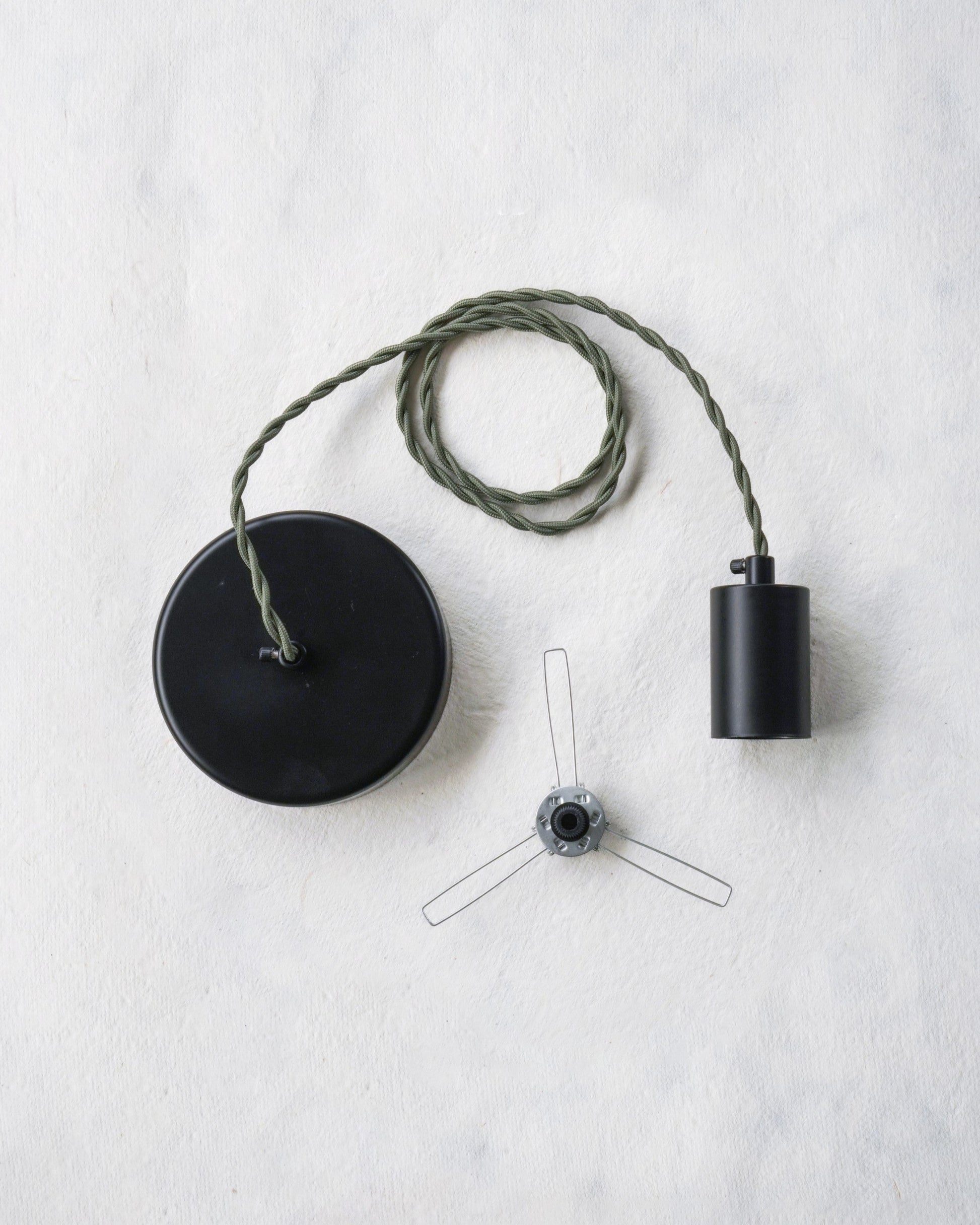 Pendant lamp with sage green cord, black canopy and socket and a lampshade holder on a white background