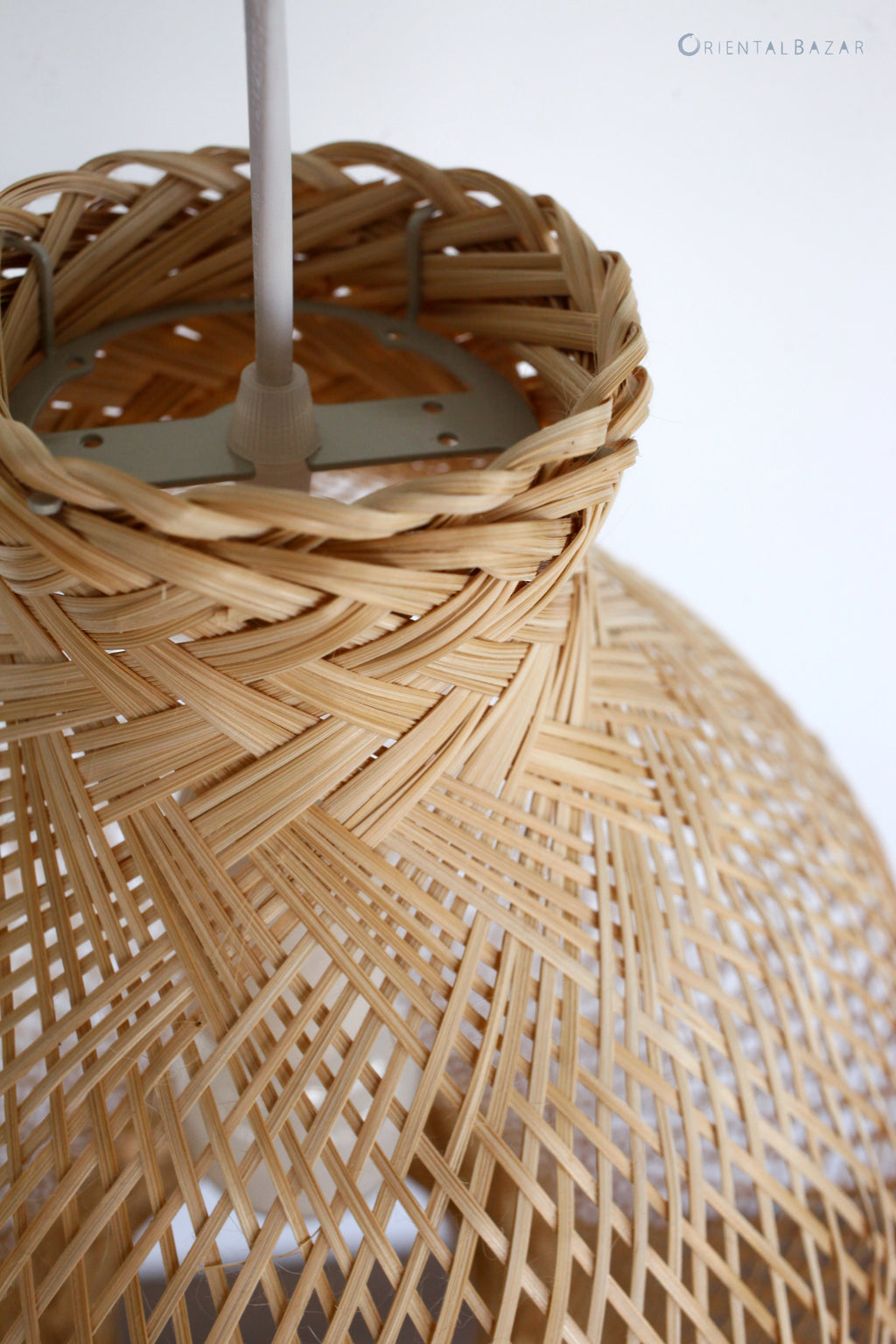 Close-up of a woven bamboo lampshade with a white ceiling cord fixture.