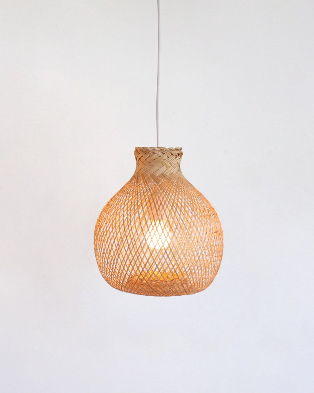 Woven bamboo pendant light hanging against a white background