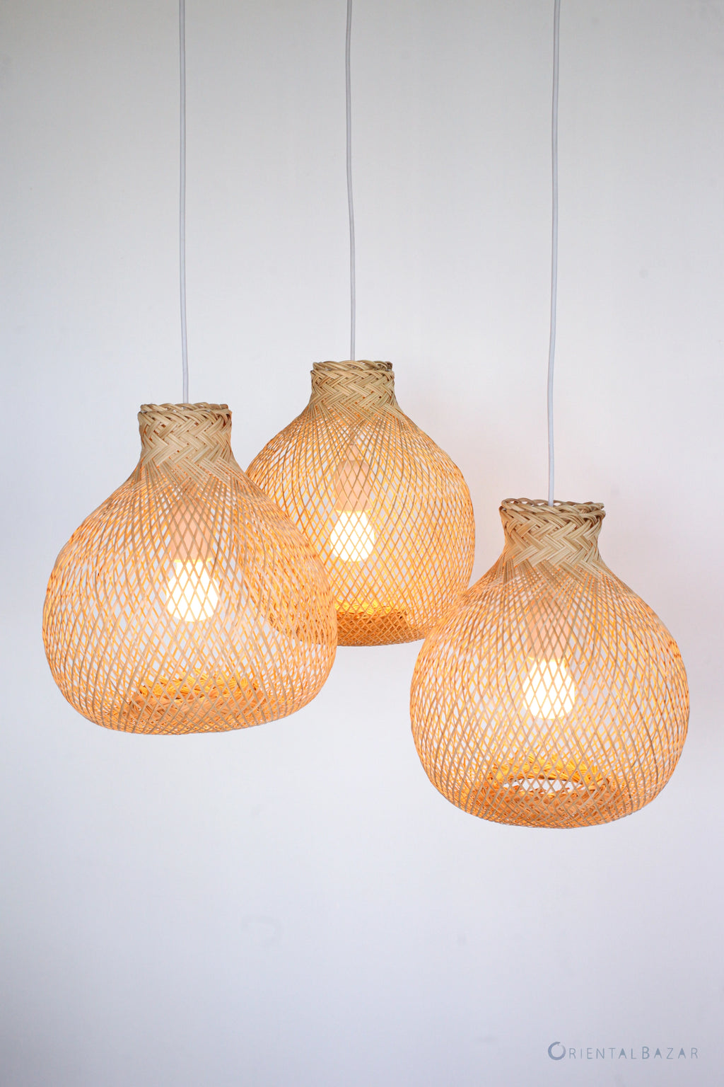 Three boho woven bamboo pendant lights on a white background