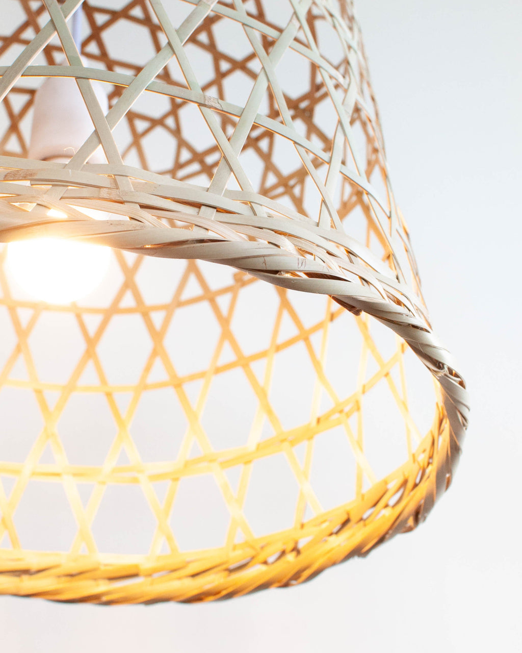 Woven bamboo lampshade with a soft glow on a light background