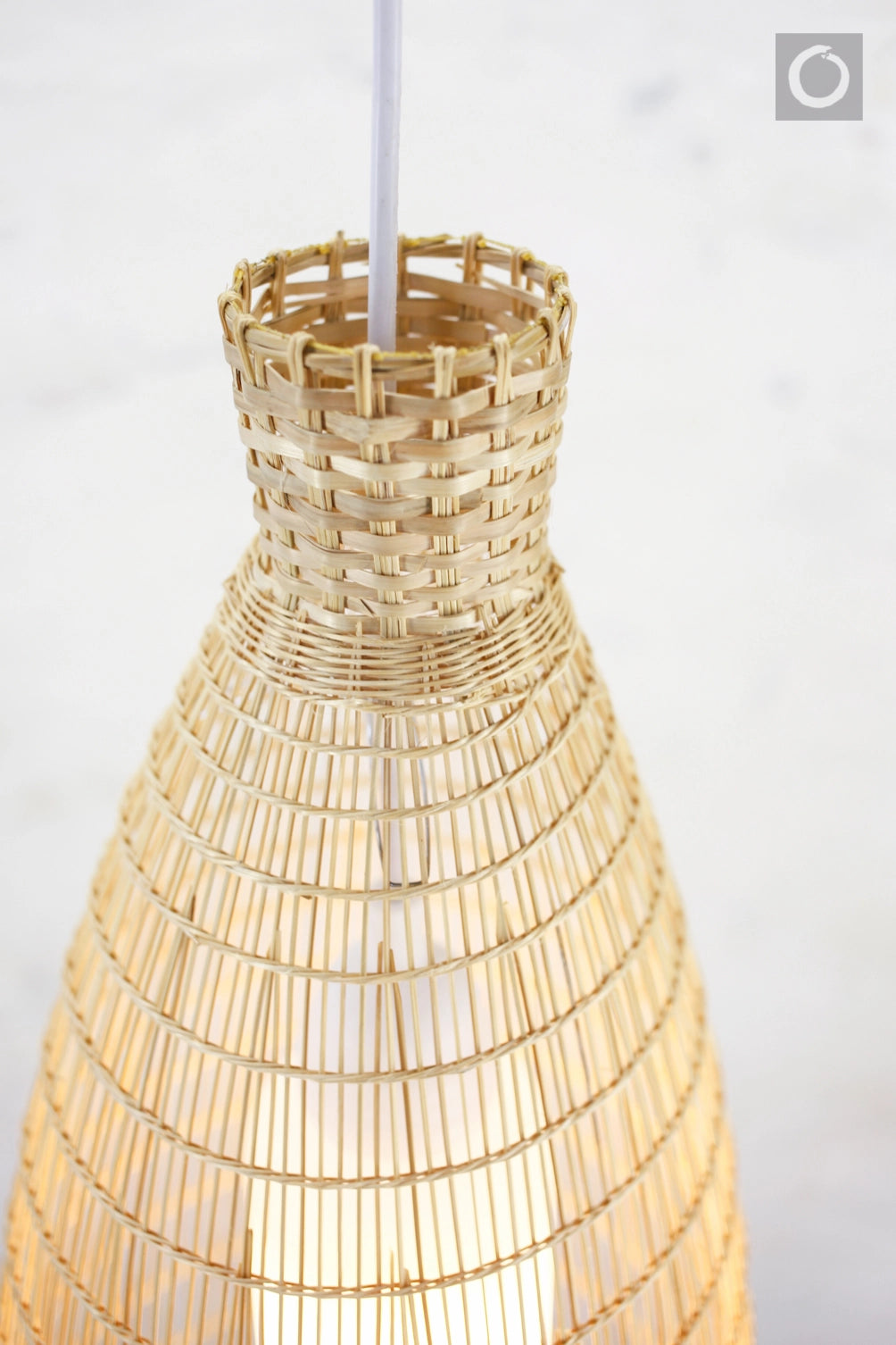 Closeup of a woven bamboo lampshade on a white background
