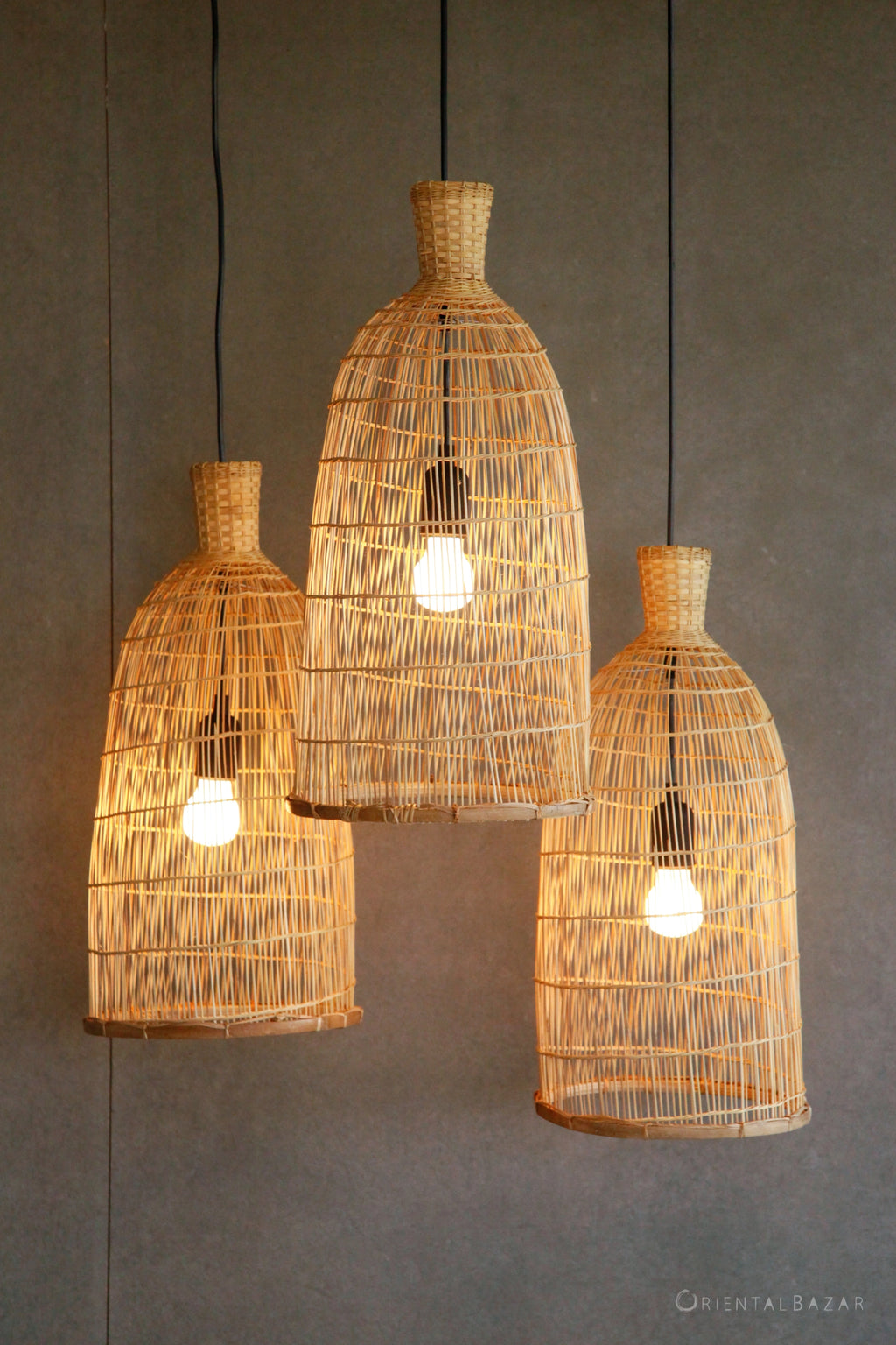Three woven bamboo pendant lights on a gray background