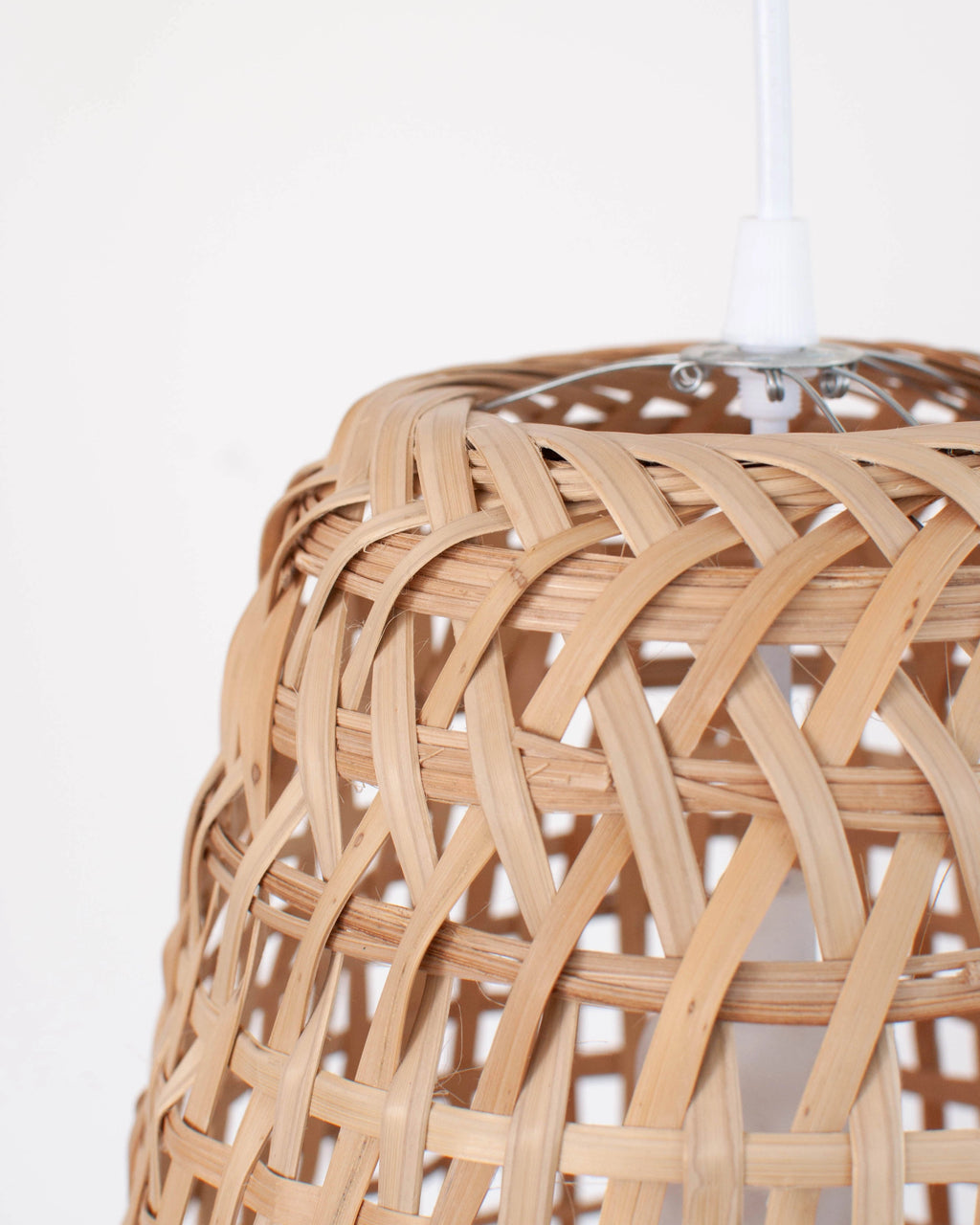 Closeup of the top part of a woven bamboo pendant light against a white background