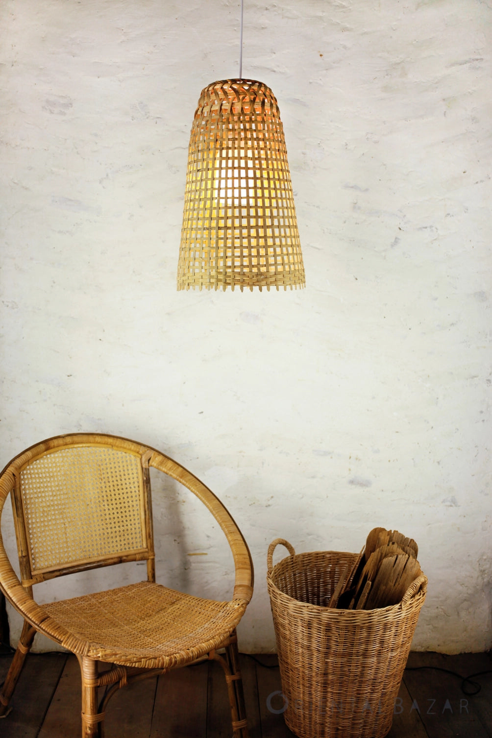 Rattan chair and basket with a woven bamboo pendant light against a white wall.