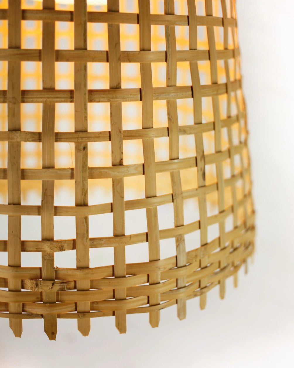 Closeup of the bottom rim of a woven bamboo lampshade on a white background