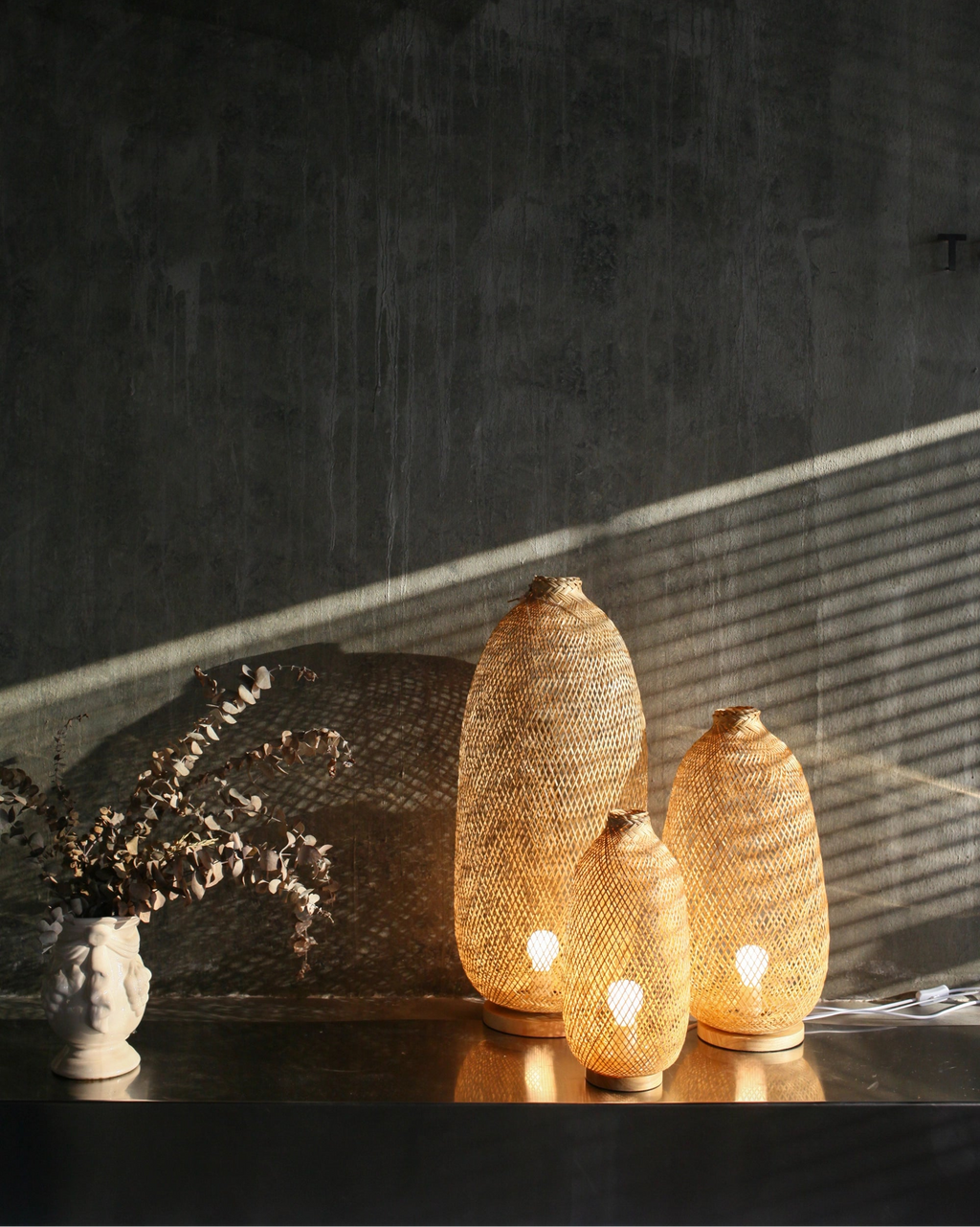 Three woven bamboo lanterns glowing warm light, with a dark background.