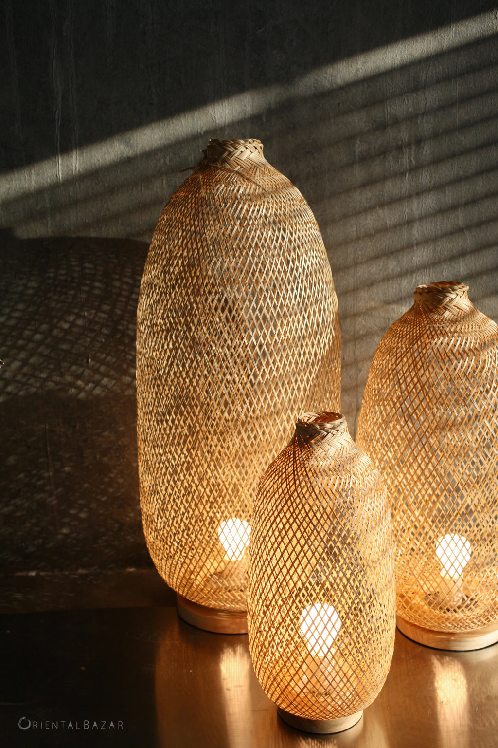 Three woven bamboo lanterns emitting a warm glow on a rustic wall