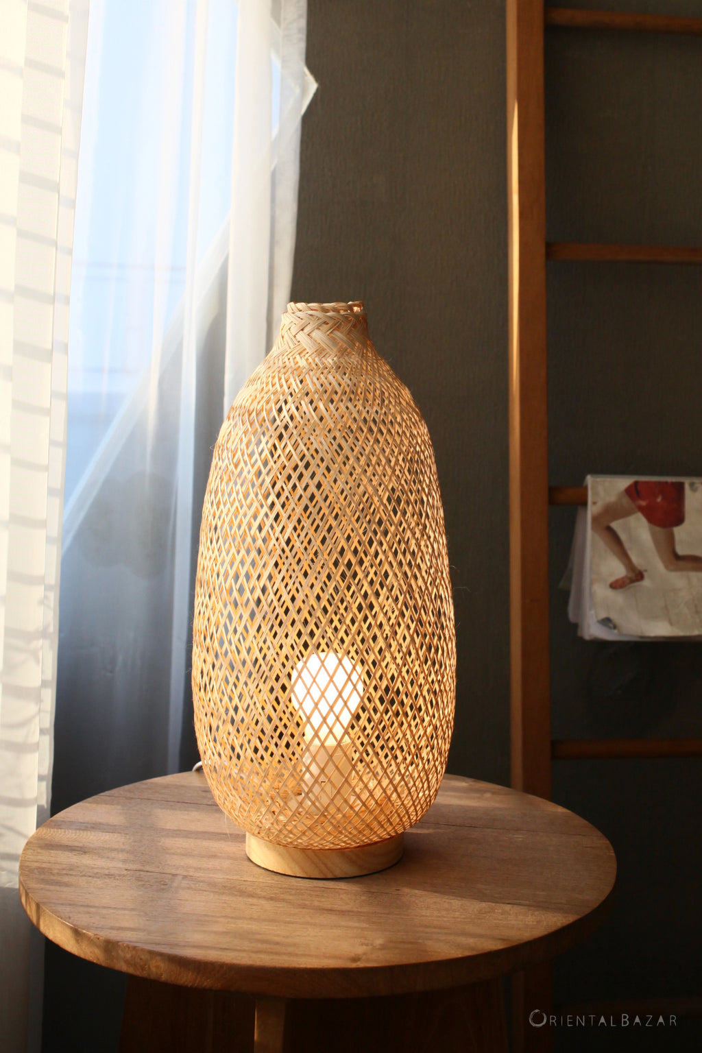 Woven bamboo table lamp on a wooden side table with a blurred background