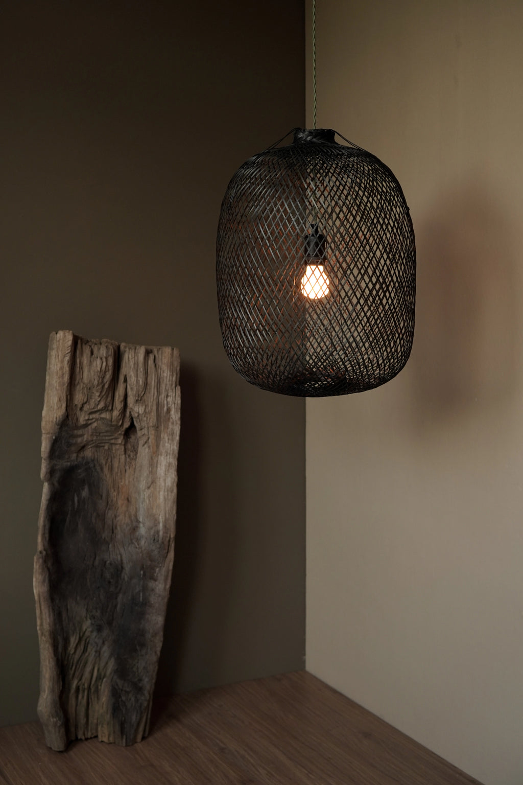 Black woven bamboo pendant light on a earth taupe and brown wabi-sabi background