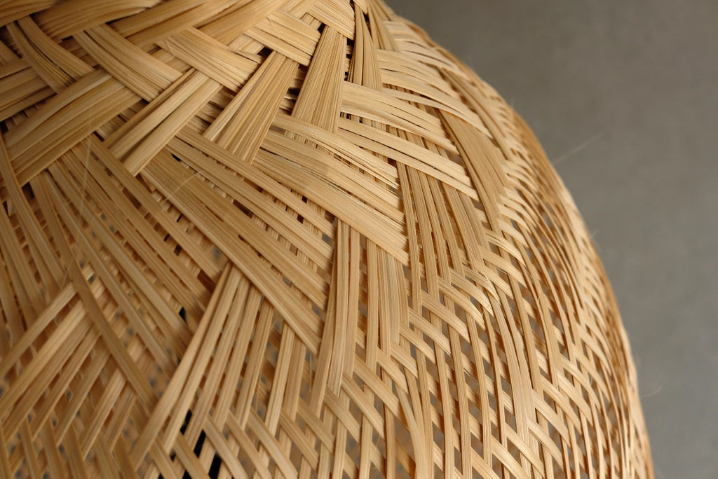 Close-up of a woven bamboo lampshade against a neutral background