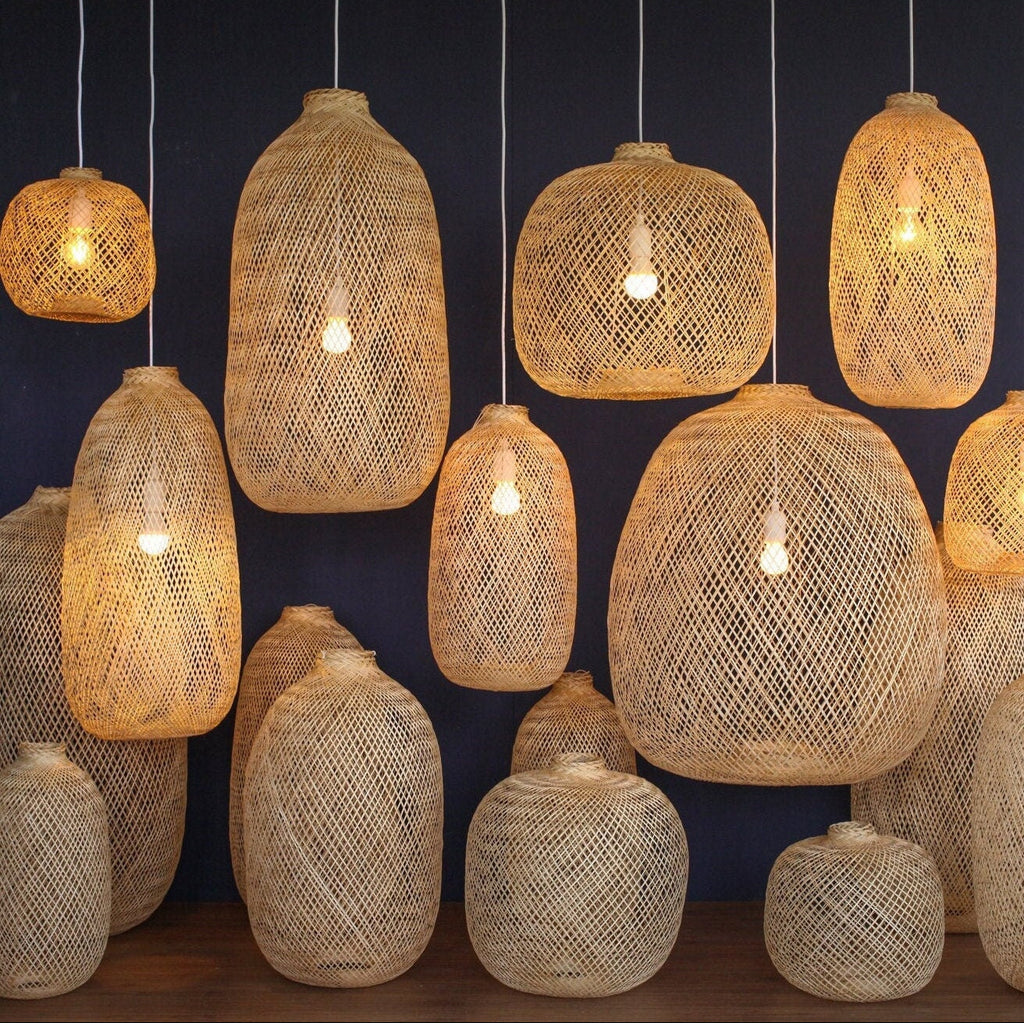 Bundle of bamboo hanging lamps of different shapes glowing warm light with a dark blue background