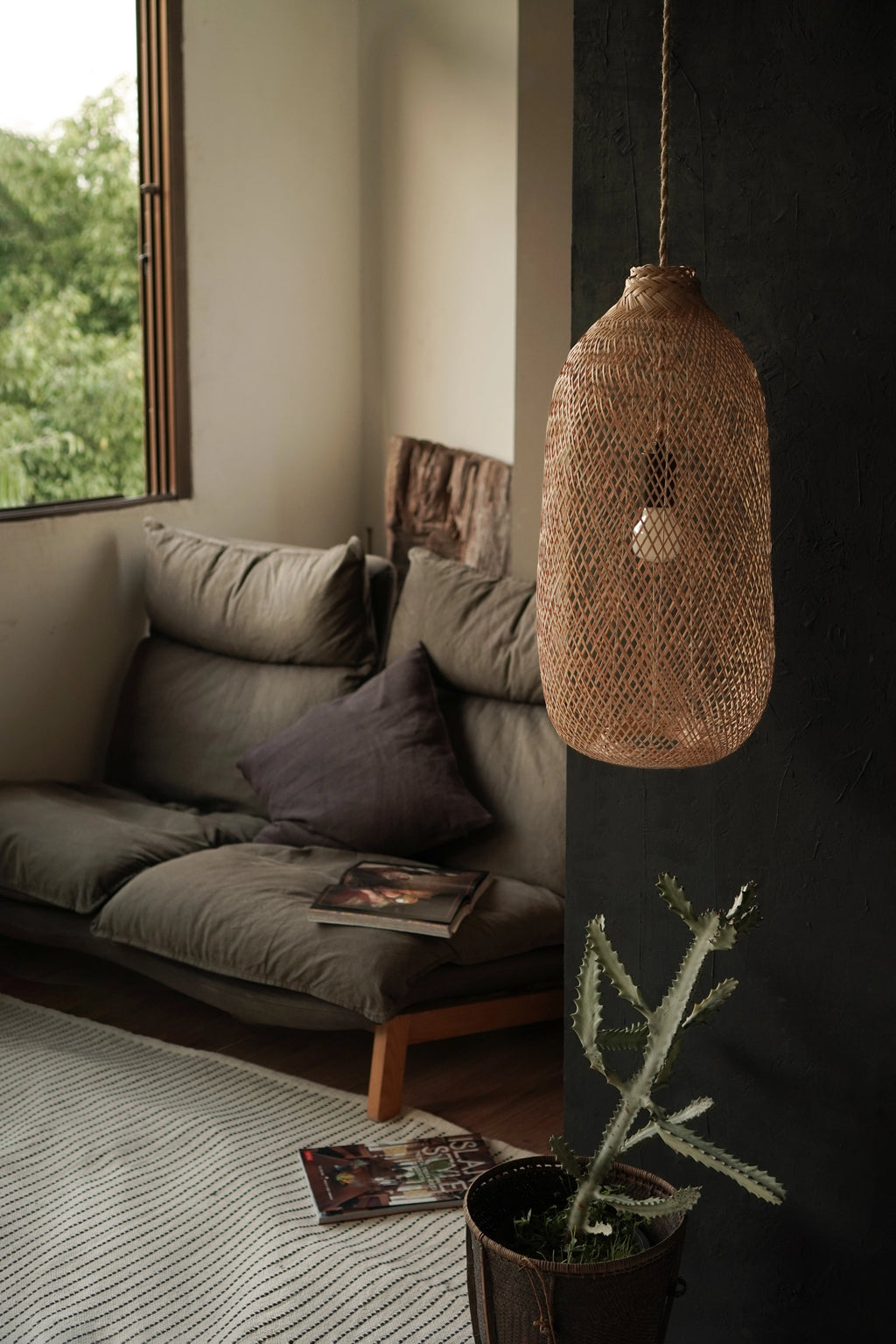 Living room with a woven bamboo pendant light, sofa, and window view