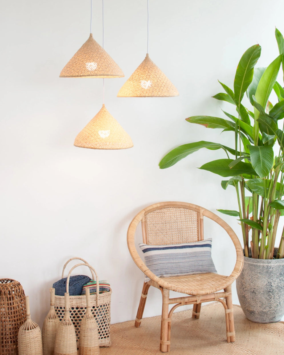 Rattan chair with woven baskets and pendant lights in a room with a plant.
