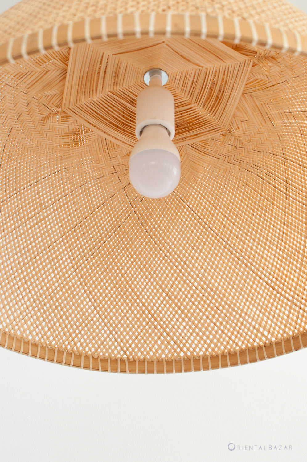 Close-up of a woven boo lampshade with a light bulb inside on a white background