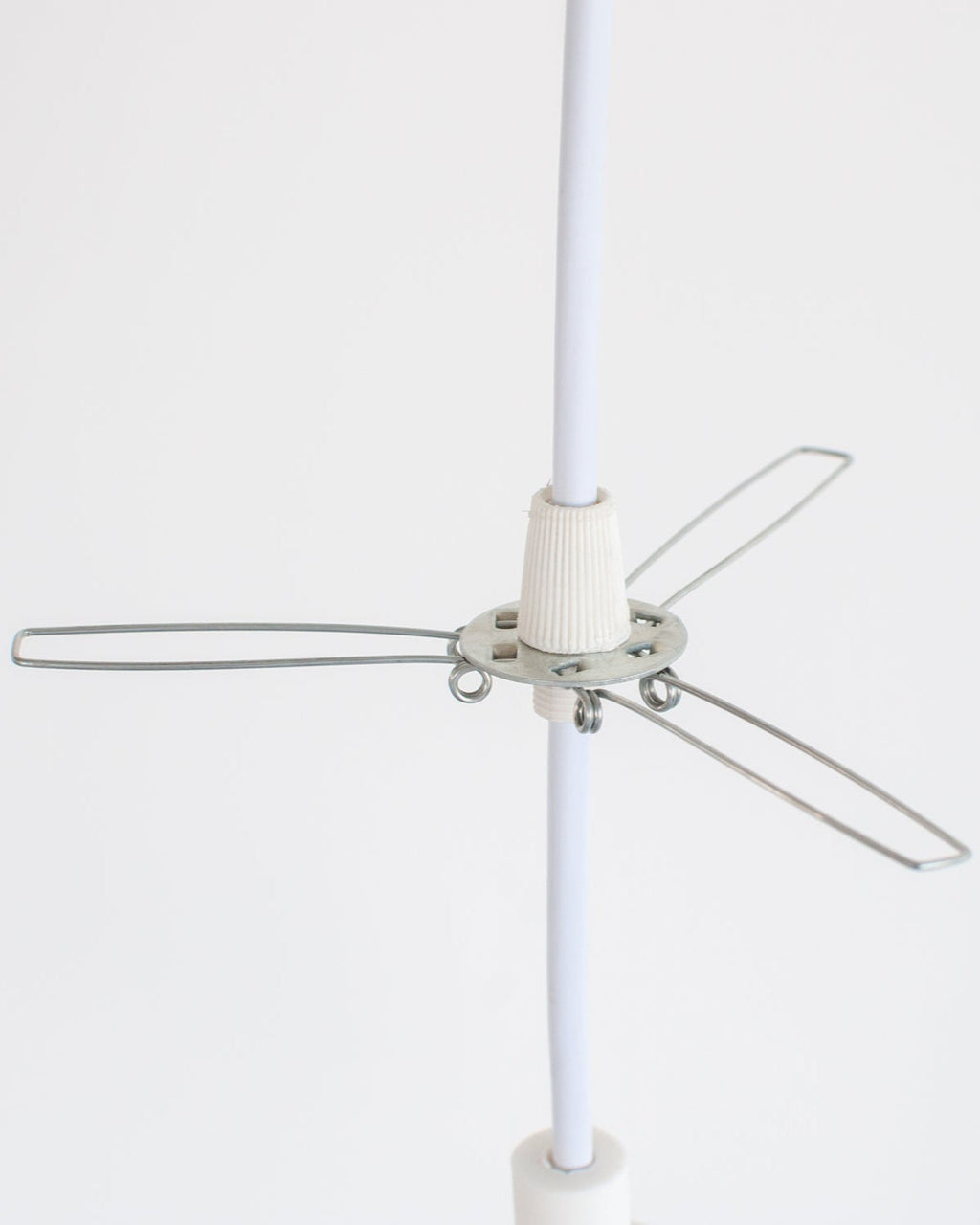 Lampshade holder metal bracket installed on white pendant light cord on a white background