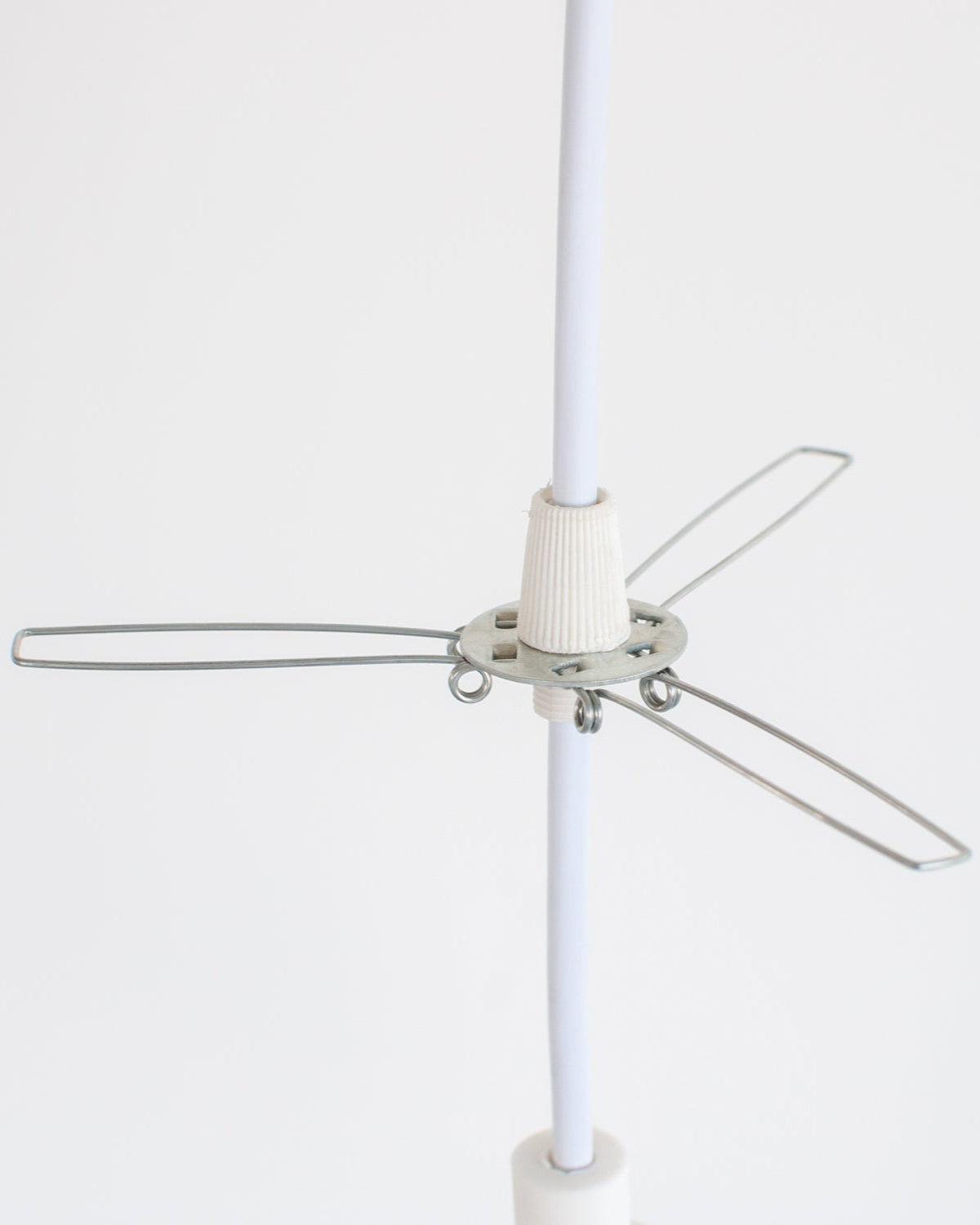 Lampshade holder metal bracket installed on white pendant light cord on a white background