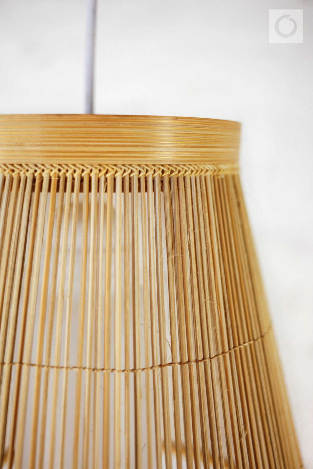 Close-up of a woven bamboo lampshade against a white background