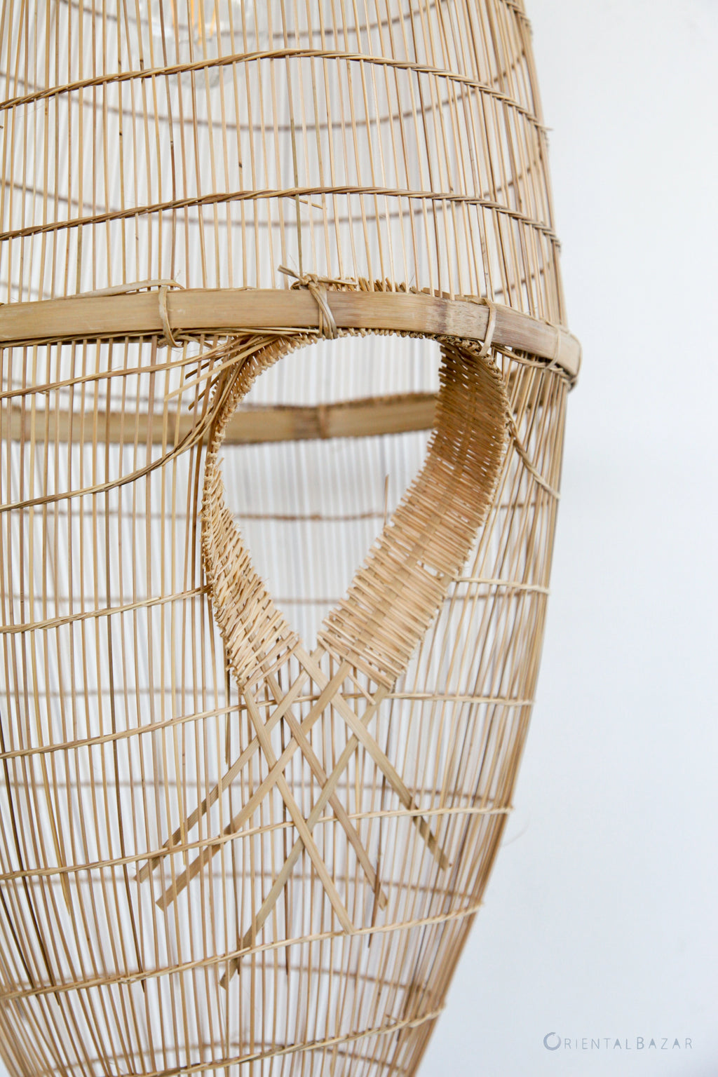 Close-up of a woven bamboo pendant light on a plain background