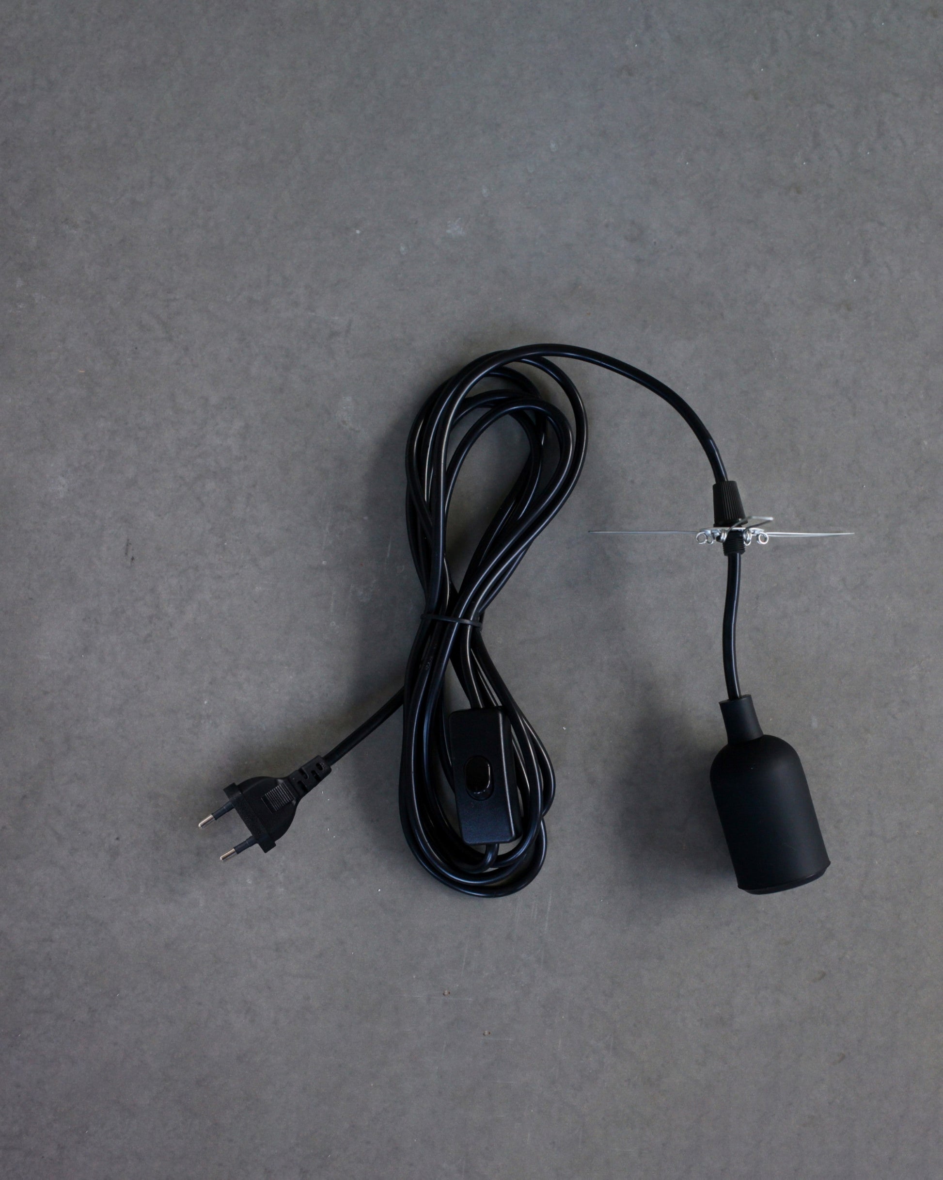 Black lamp cord with plug on a gray background