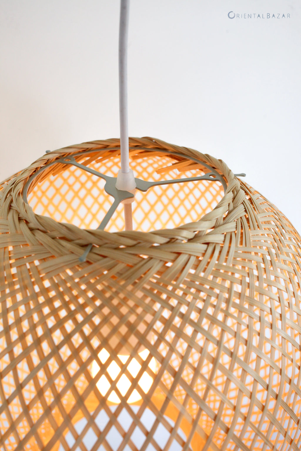 Closeup of a woven bamboo pendant light with a ceiling fixture on a white background