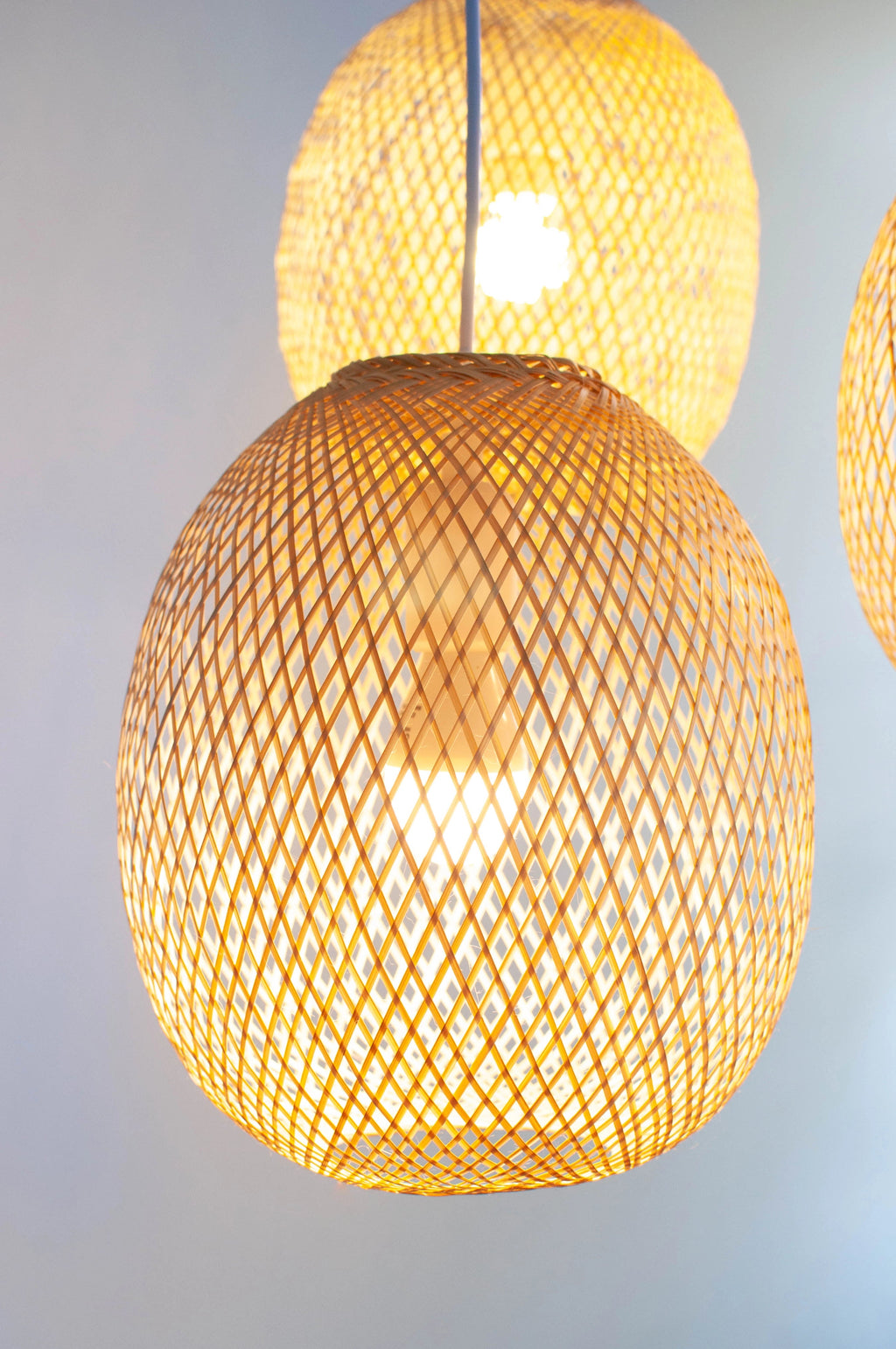 Woven bamboo spherical lampshades with a soft glow on a light background