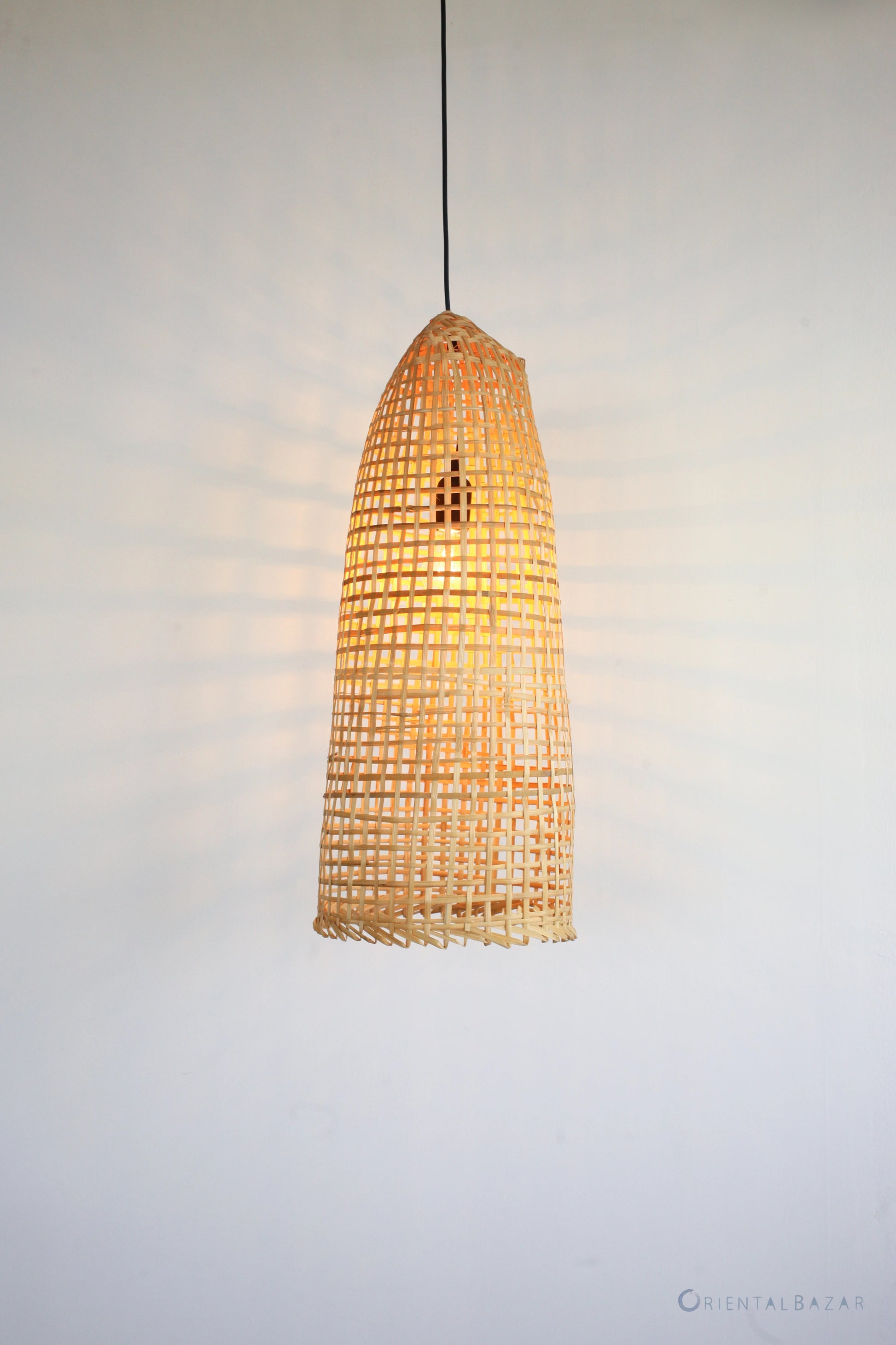 Woven bamboo pendant light on a plain background