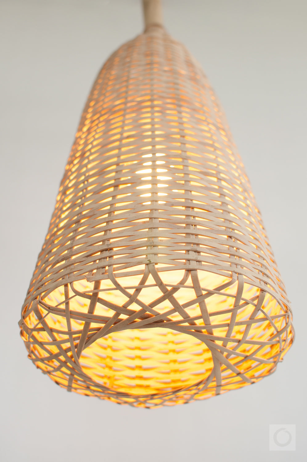Bamboo wicker pendant light with warm glow on a neutral background