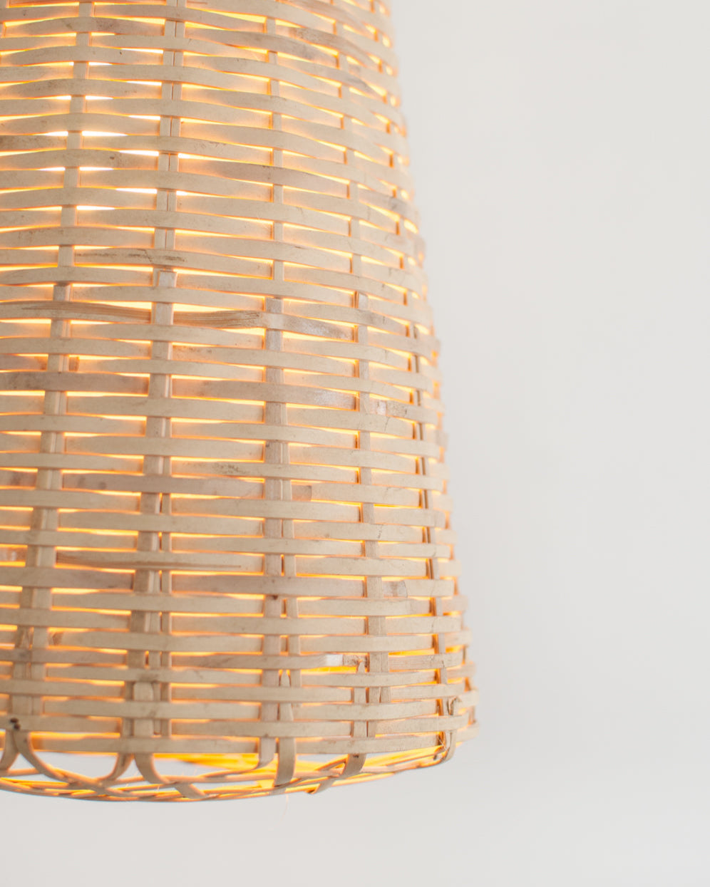 Closeup of the bottom of a woven bamboo pendant light on a white background