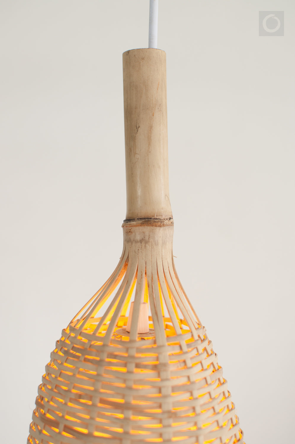 Closeup of the top of a woven bamboo pendant light on a white background